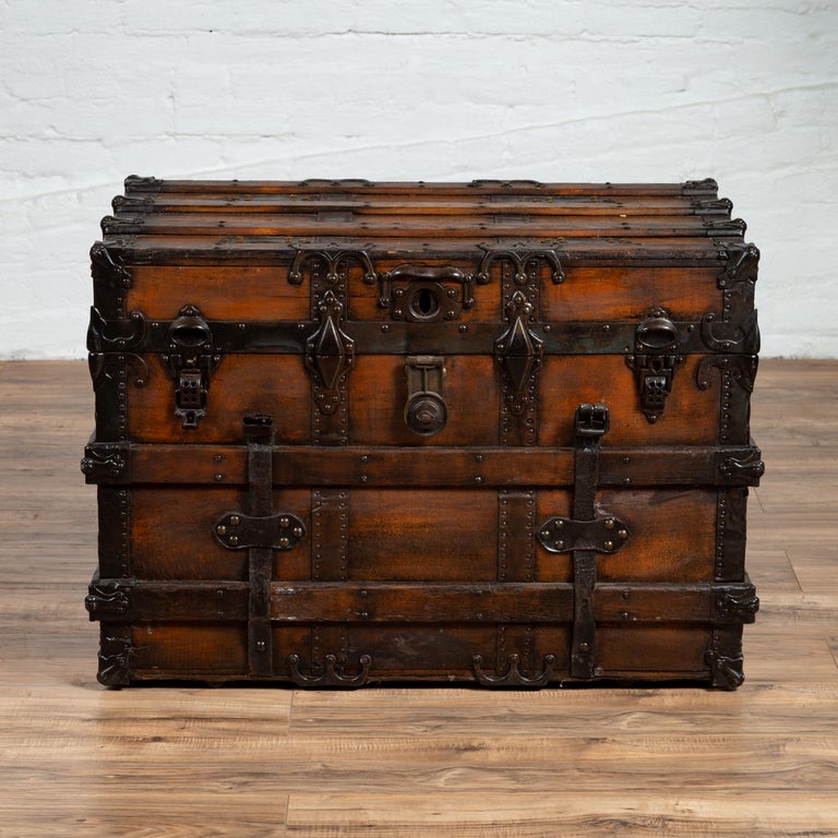 An antique Indonesian travel treasure chest from the early 20th century with leather details and brown patina. Charming our eyes with its dark hue and intricate details, this Indonesian travel treasure chest will make for a strong decorative accent.