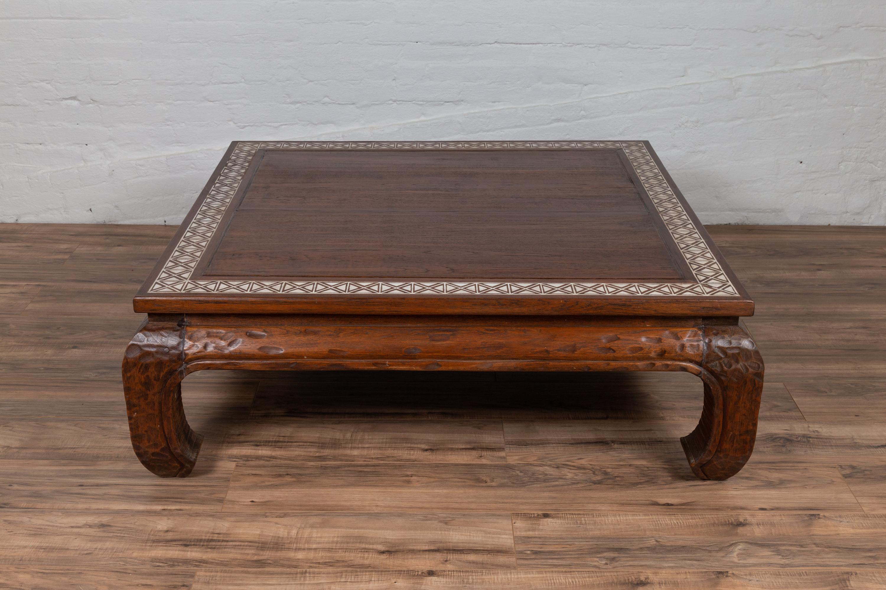 An antique Indonesian teak coffee table from the early 20th century, with X motifs on white ground, inspired by a tribal design. Born in Indonesia during the early years of the 20th century, this coffee table features a square top, adorned on the