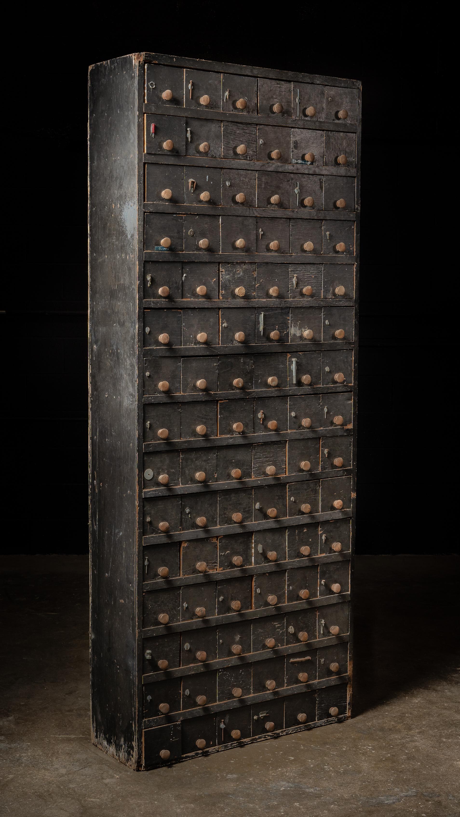 Cette impressionnante quincaillerie antique à 90 tiroirs était à l'origine utilisée dans un atelier ou un magasin général. Cette pièce imposante a été construite pour conserver d'innombrables petits composants - tels que des écrous, des boulons, des