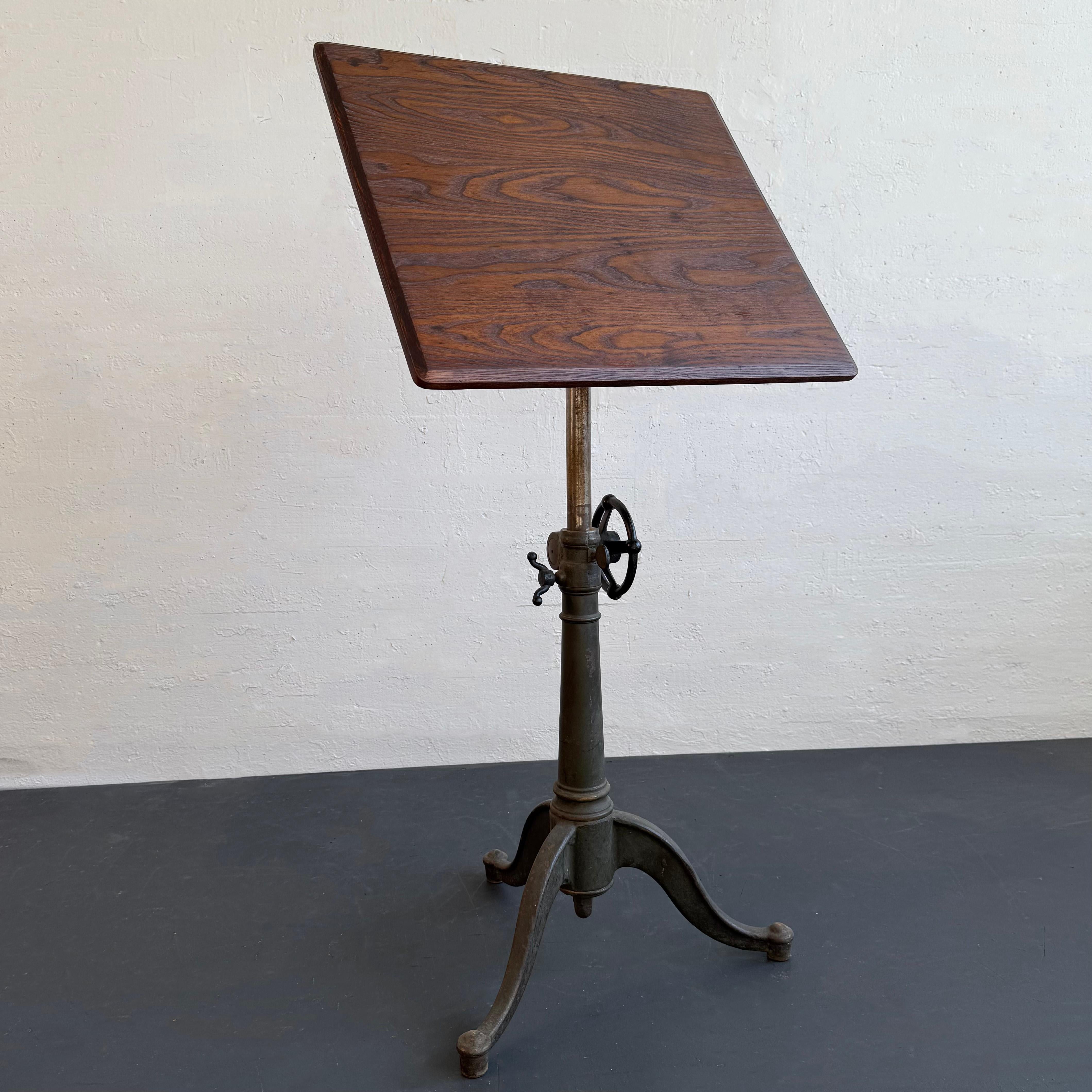 Questo antico cavalletto industriale per artisti o tavolo da disegno ha un piano in rovere massiccio di 24 x 22 pollici su una base in ghisa regolabile in altezza e inclinazione con il marchio del produttore Washburn Shops. L'altezza è regolabile da