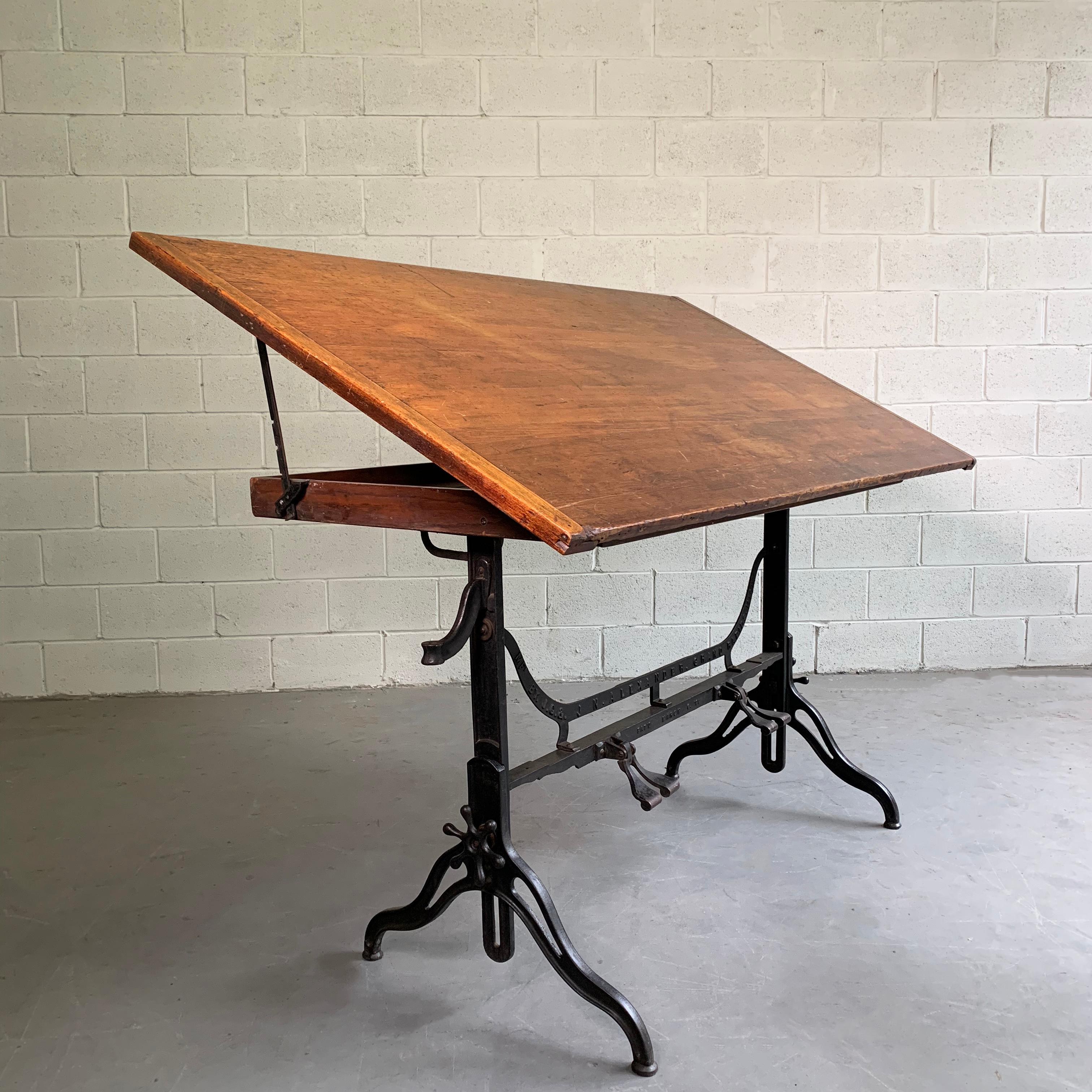 Large, antique, drafting table by J.G. & J.N. Alexander, Grand Rapids, MI, patent 1894 features a cast iron base with footrests that adjusts from 38-45 inches height and an adjustable pine top that tilts incrementally to 28 degrees to the horizon