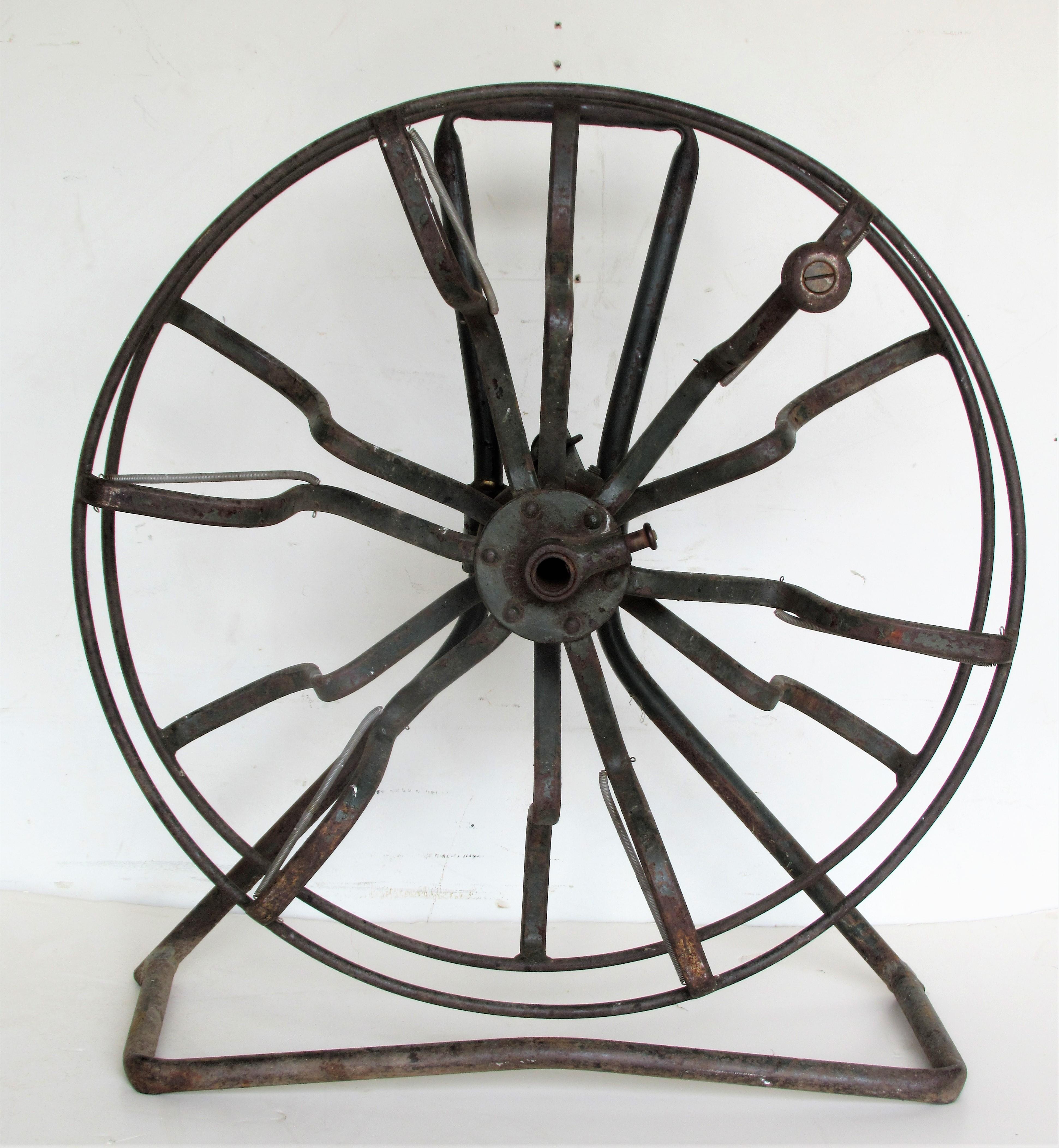 Antique American industrial iron fire hose reel in all original beautifully aged dark green painted surface with period wood knob and all gears present and working. Great looking sculptural object, circa 1900-1920.