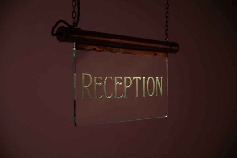 A large illuminated glass and brass directional sign made in England. c.1920.

Brass frame housing the internal illuminations above polished plate glass deep etched with 'Reception'. No makers mark, but very similar in design and build quality to