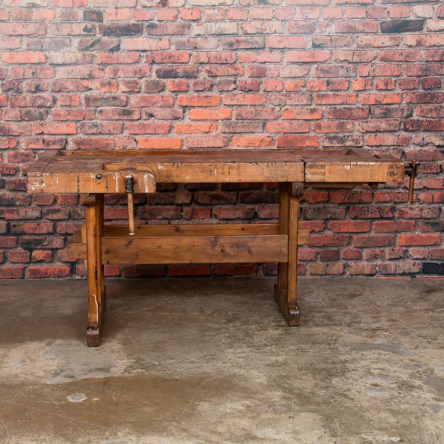 The depth of patina on this workbench comes from years of constant use. It has two wooden vices and a recessed tray where the carpenter would lay his tools. The traditional trestle base allowed it to be assembled and taken down/moved more easily.