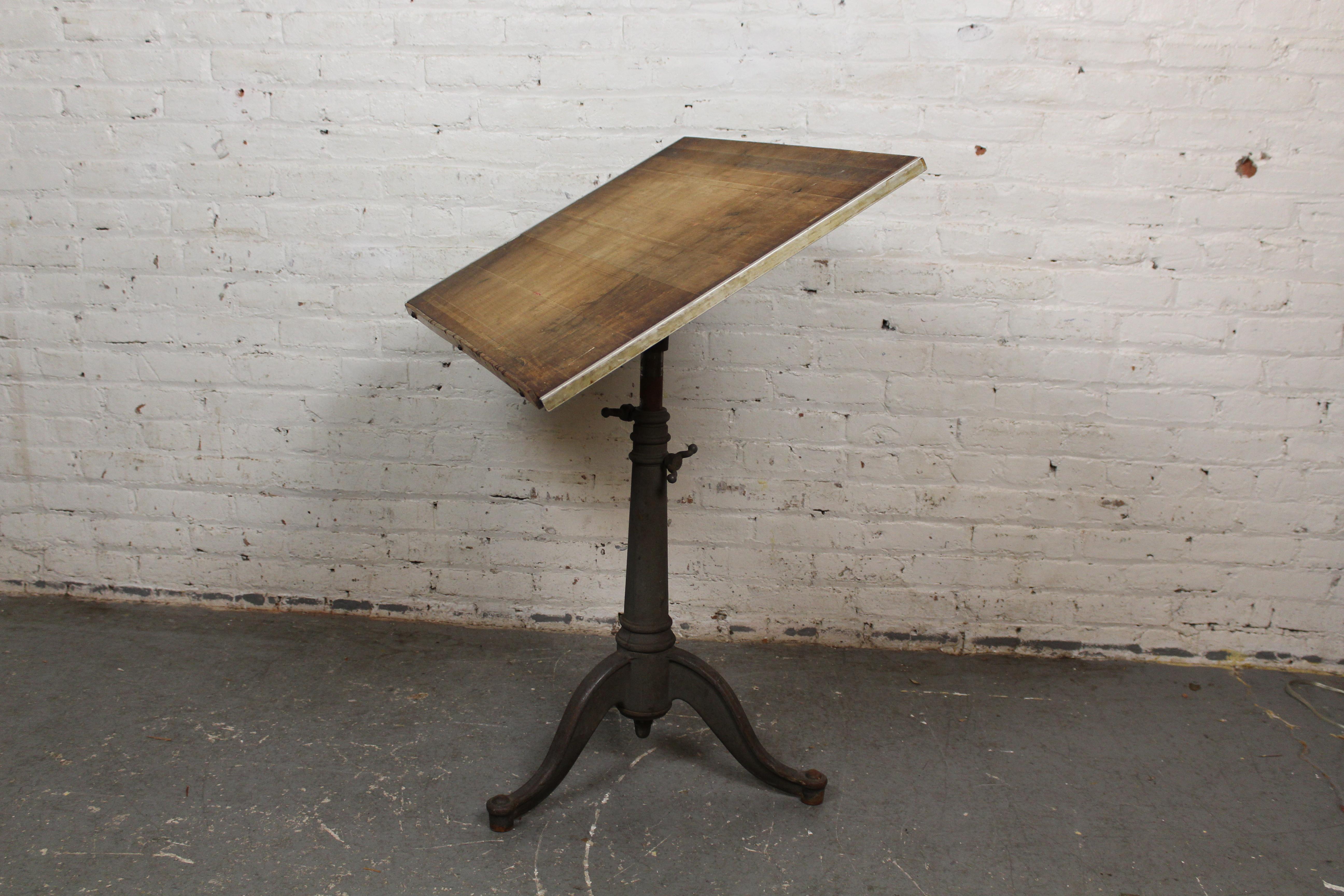 Relieve all the splendor and charm of 19th century industrialism with this quaint antique drafting table. Featuring an elegant cast iron pedestal base and an adjustable solid wood desktop with remarkable patina, this table blurs the line between