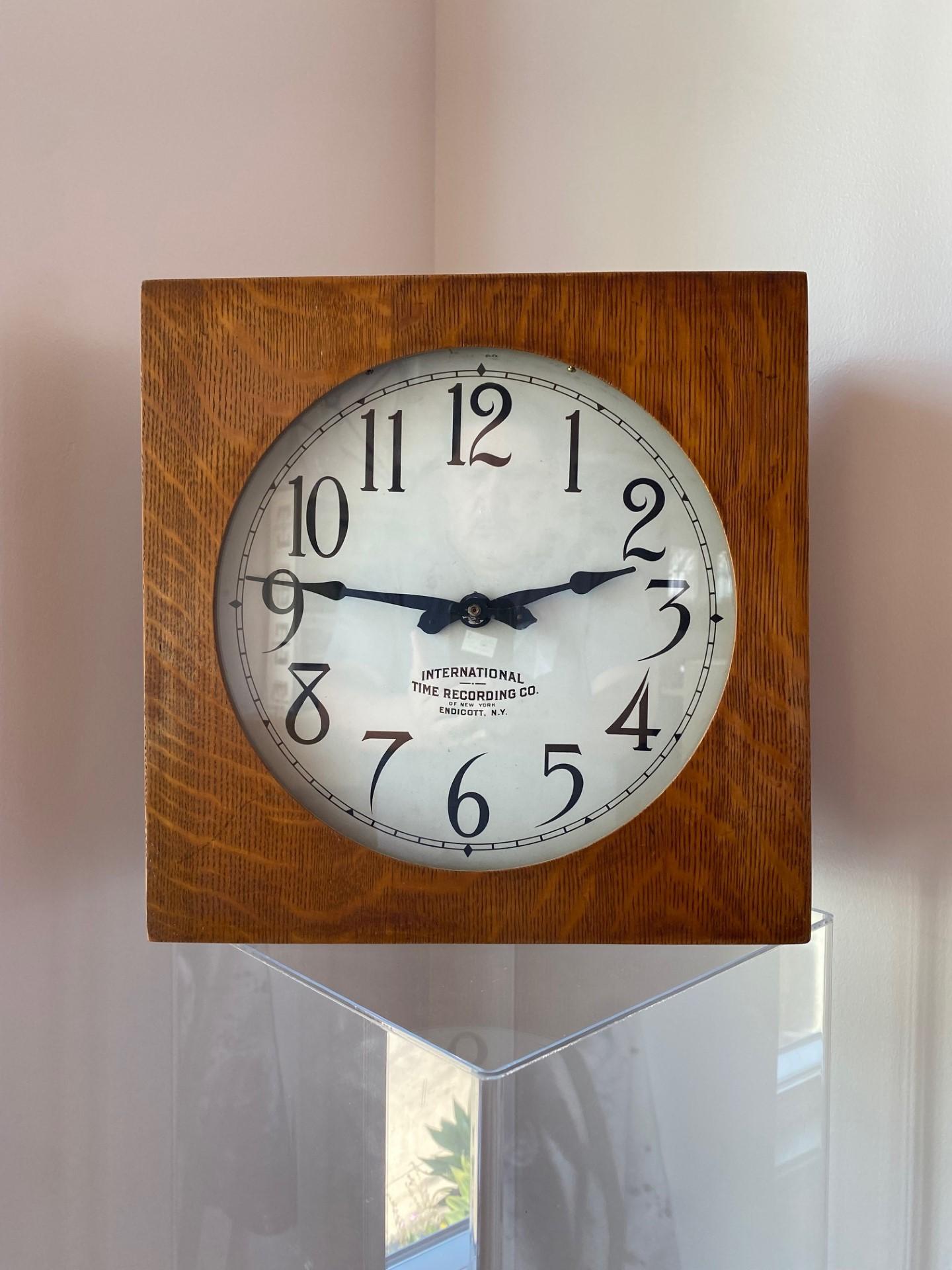 Beautiful antique clock from 1925 by the International Time Recording Company.  This piece originally was used in commercial/industrial settings.  The timepiece is encircled in a square shape wood base with glass on the front. Unique and nostalgic