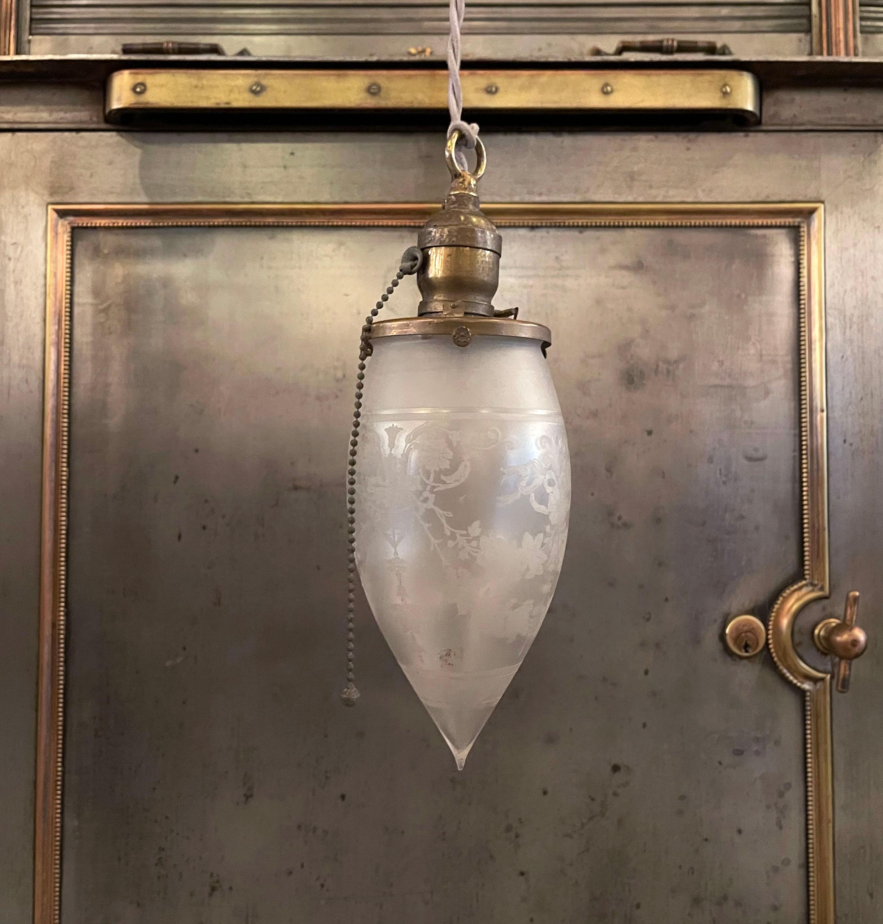 Antique, late 19th century, industrial pendant light with frosted glass, teardrop shade and brass pull chain fitter is newly wired with beige braided cloth cord to hang at an overall height of 83.5 inches.