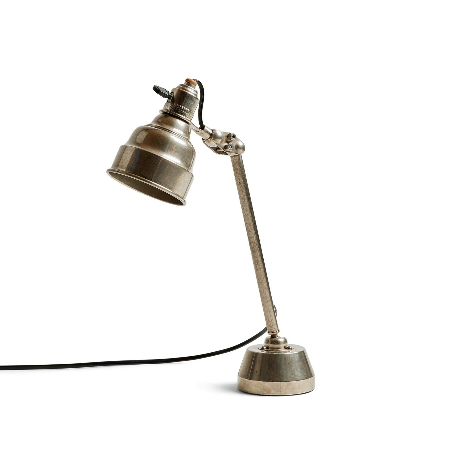 Un'elegante lampada da tavolo nichelata con stelo e paralume articolati.