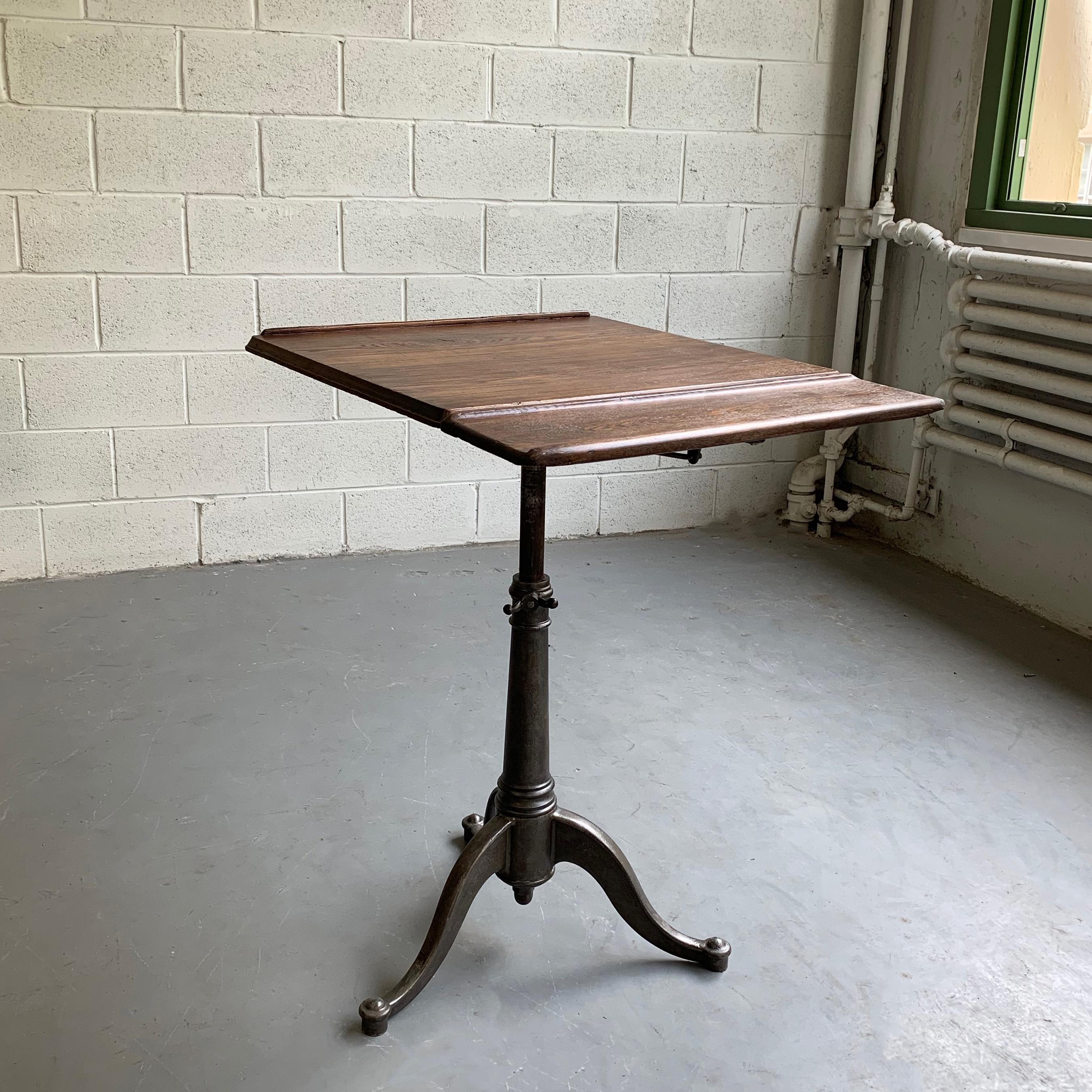 Antique, Industrial, artist rendering easel table features an expandable, dark, oak top from 22 - 28.5 inches with a 6.5 inch lip and tilt and height adjustable, cast iron, pedestal base that adjusts from 29 - 40 inches.