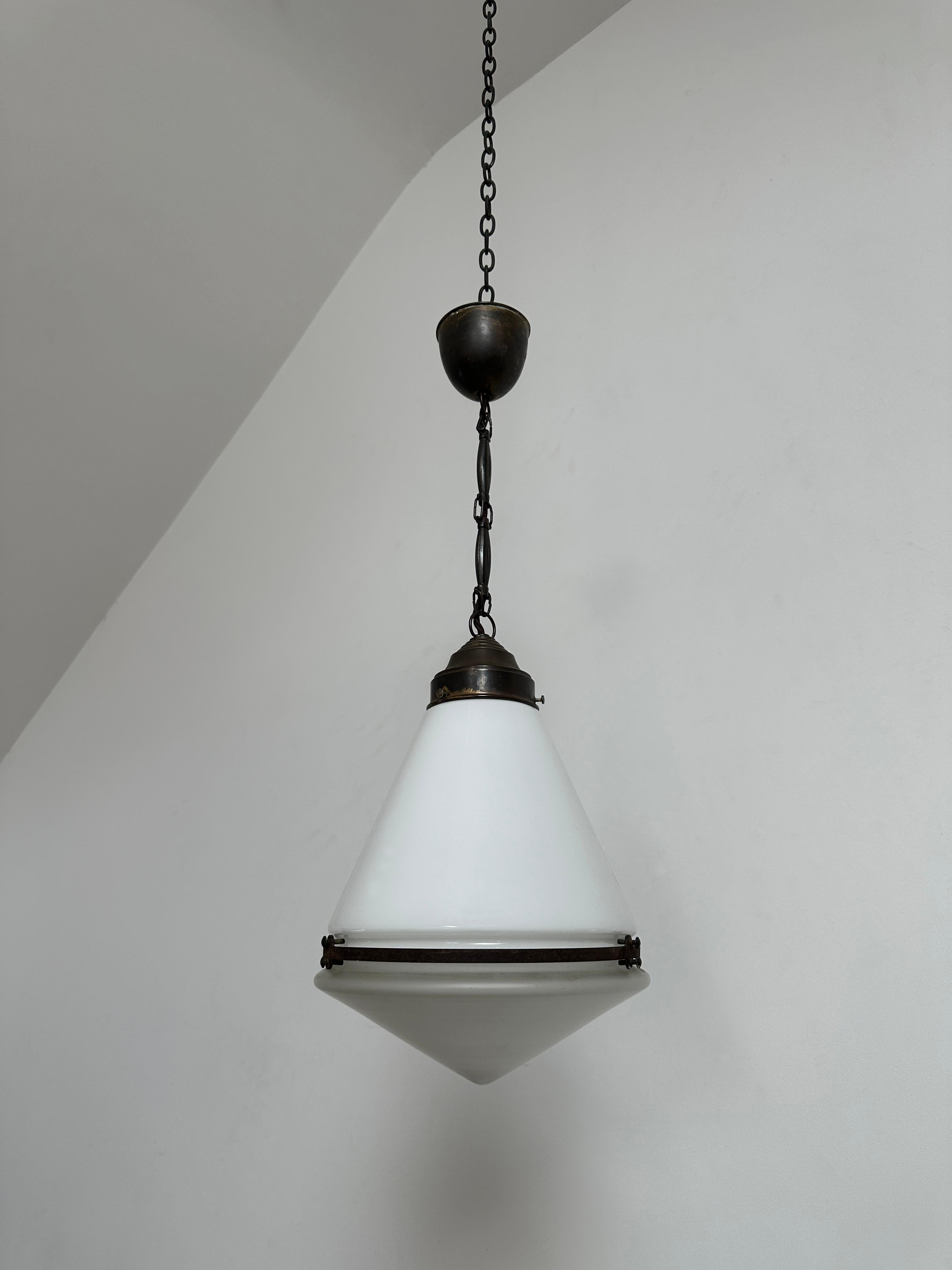 - Un original e increíblemente raro colgante cónico de techo de Peter Behrens para AEG, Alemania, hacia 1920. 
- La lámpara tiene dos partes de cristal, la superior opalina y la inferior triangular esmerilada. 
- Fantástico estado original, una