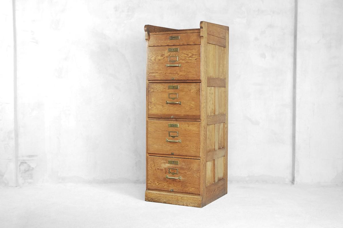 This antique cabinet was manufactured in England in first half of the 20th century. It is made from solid oak wood. It has four deep drawers with compartments and one smaller under the top. The drawers have a file system and handles in brass. One