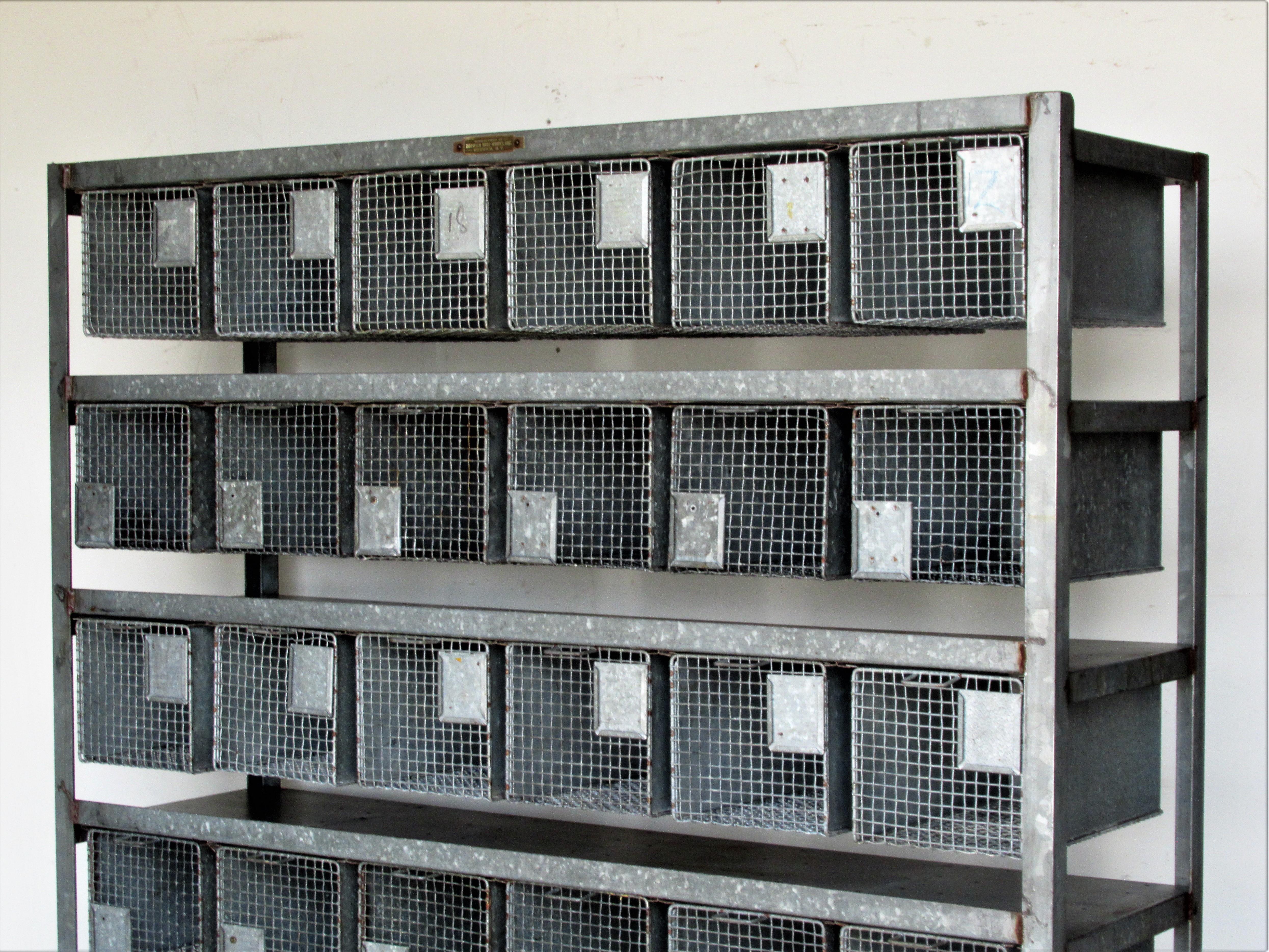 Antique American industrial freestanding galvanized metal rolling rack storage system having five shelves each with six metal wire baskets that slide in and out on fitted upper tracks - thirty baskets total - each measuring 15 inches deep from