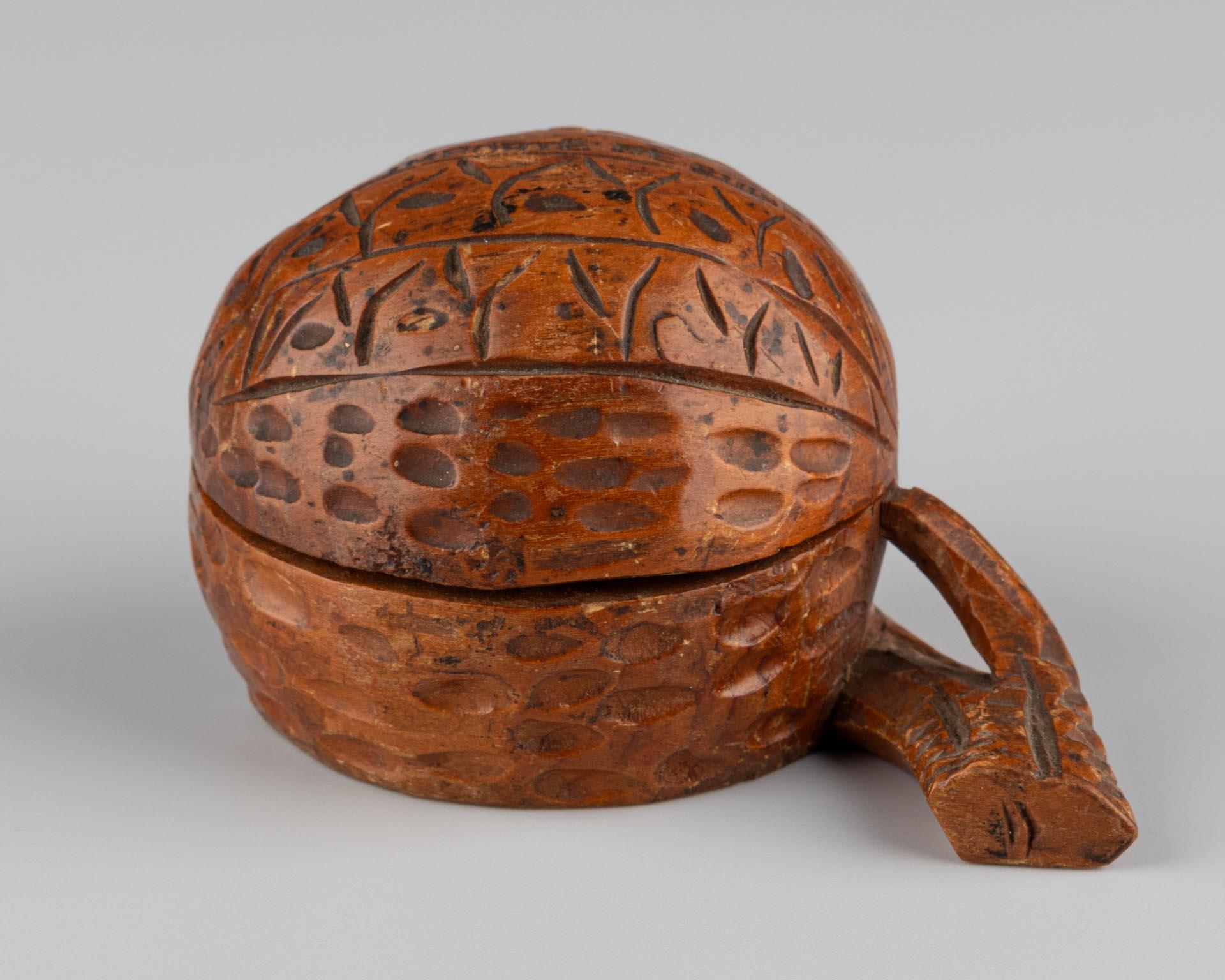 Origin: Switzerland
Material: Wood, glass
Date: c. 1900
Dimensions: H × W × D: 6 × 8 × 5 cm

Description:
Small inkwell made of carved wood in the shape of a walnut. The lid is hinged and can be opened. The exterior is decorated with punched