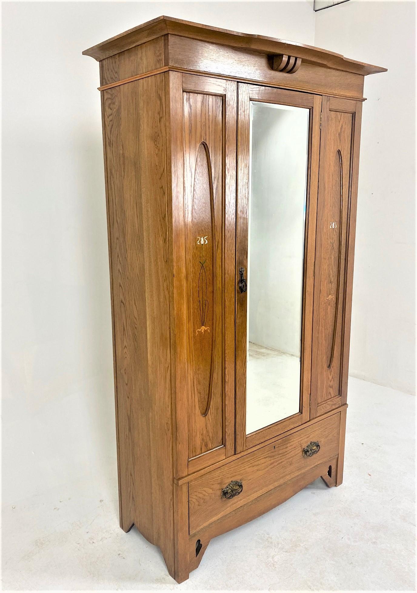 Antique Inlaid Art Nouveau Oak Armoire Wardrobe, Closet, Scotland 1910, B664

Scotland 1910
Solid Oak
Original finish
Large overhang breakfront cornice
Single bevelled mirror door opens to reveal brass hooks
Flanked by a pair of inlaid mother