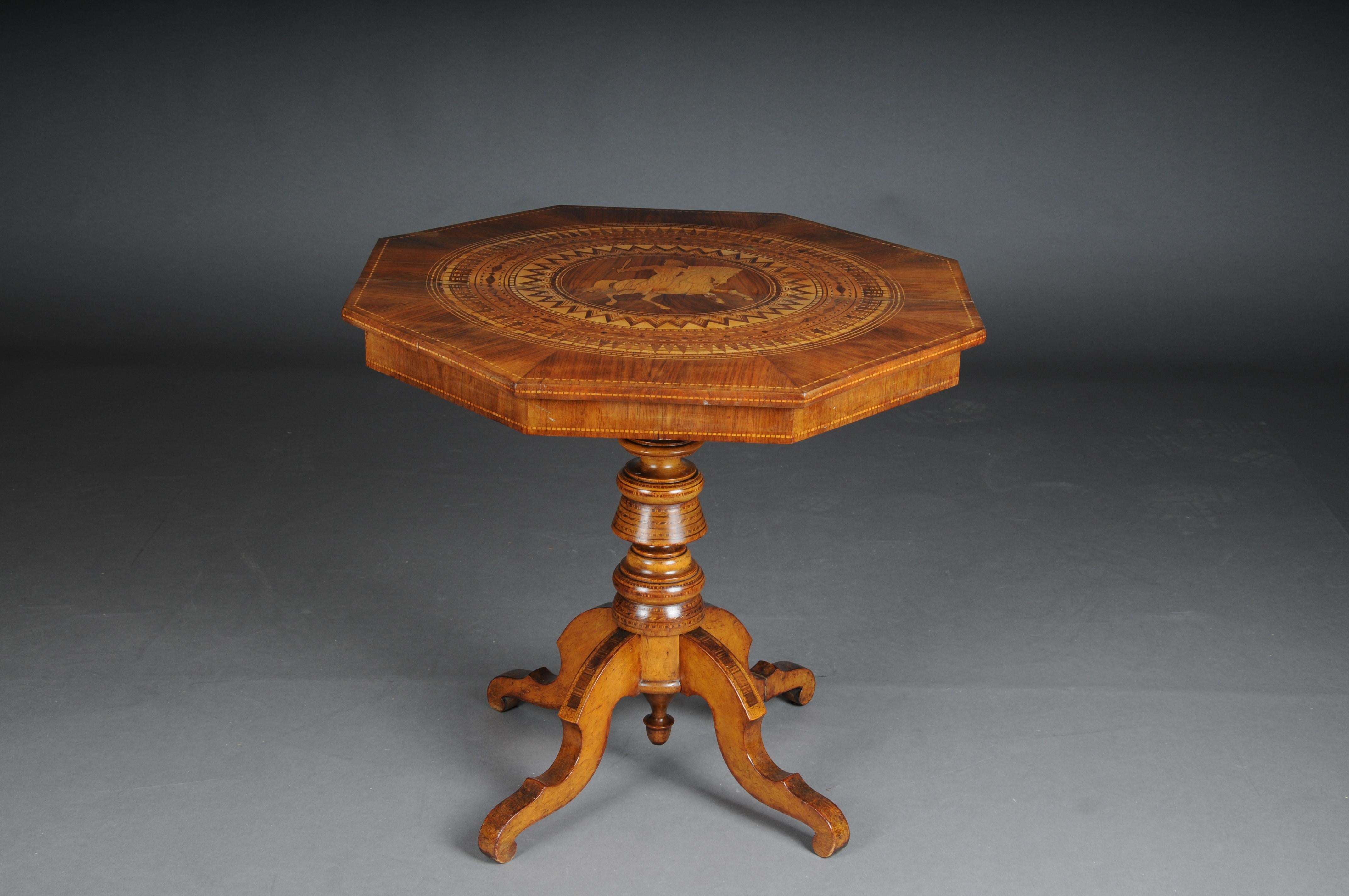 Antique inlaid baroque side table 19th century.

Solid wood body with walnut veneer. Rich marquetry on octagonal cover plate. In the middle a knightly rider on horseback. Turned and inlaid shaft connected to four long curved legs. Germany mid 19th