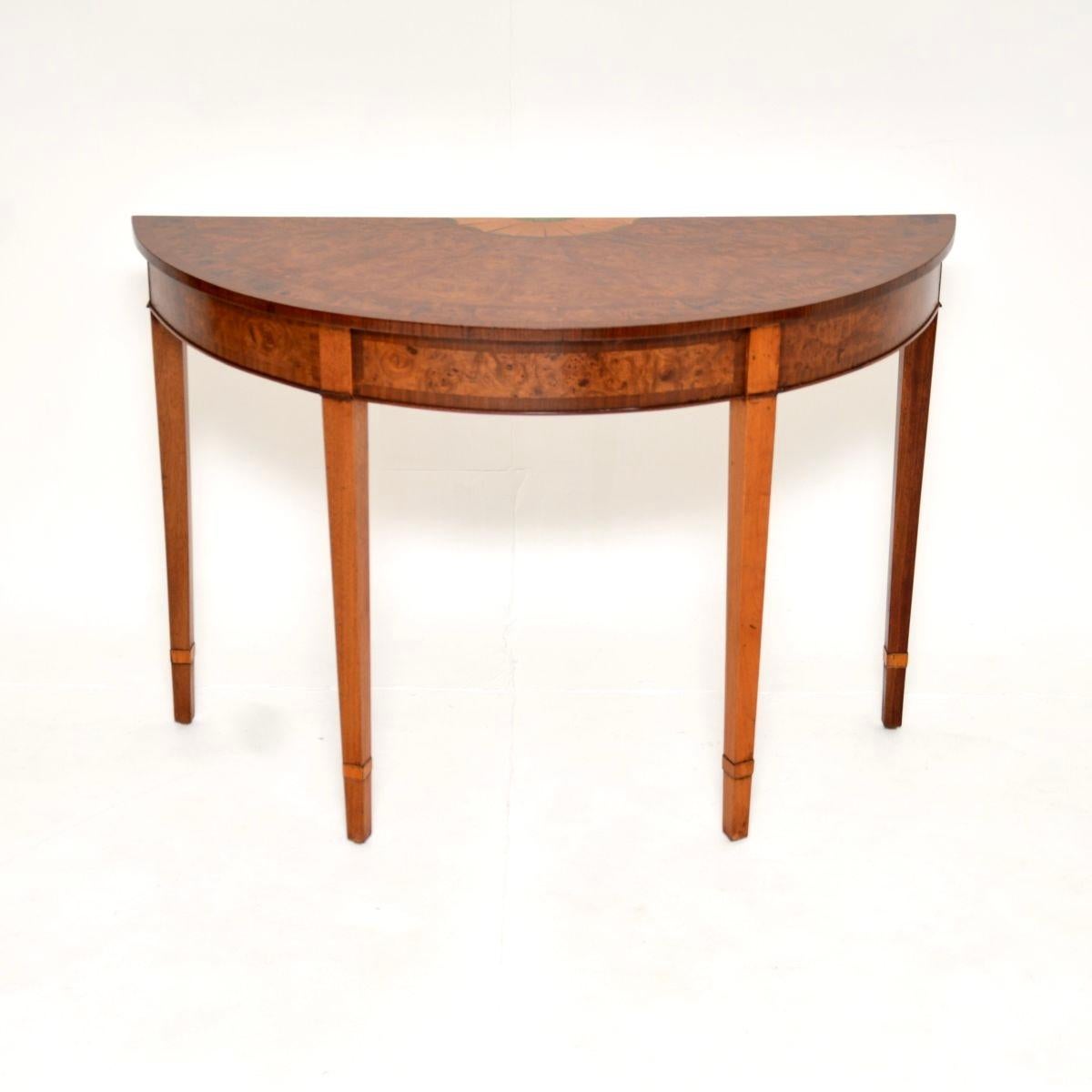 A beautiful antique inlaid burr walnut Sheraton Style console table. This was made in England, it dates from around the 1930’s.

The quality is outstanding, this is beautifully made and exquisitely designed. It has a bow front shaped top, sitting on
