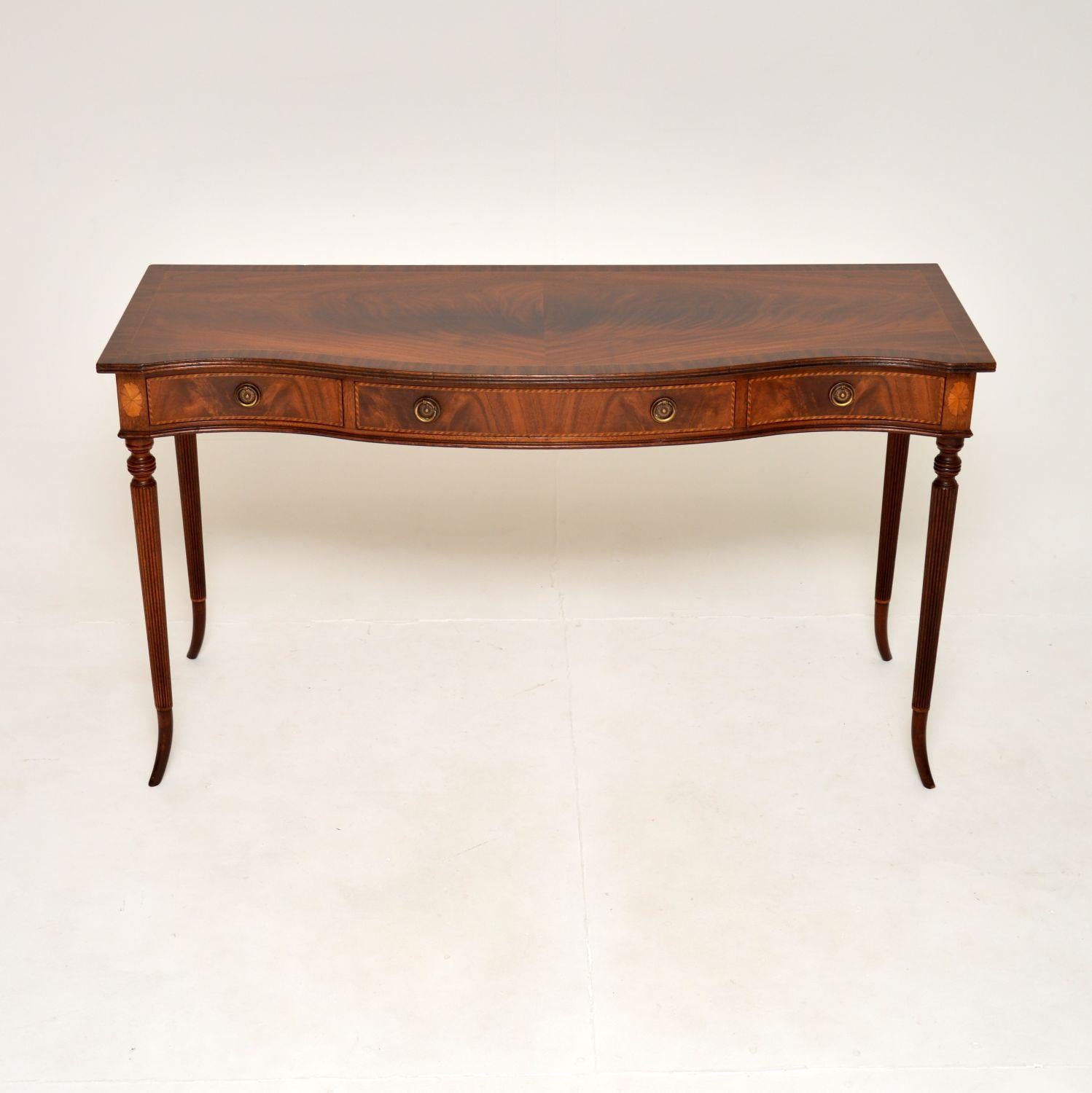 A very fine and beautifully made antique inlaid console table. This was made in England, it dates from around the 1900-1910 period.

The quality is outstanding, this has a stunning design. The top is serpentine shaped, cross banded and with a reeded