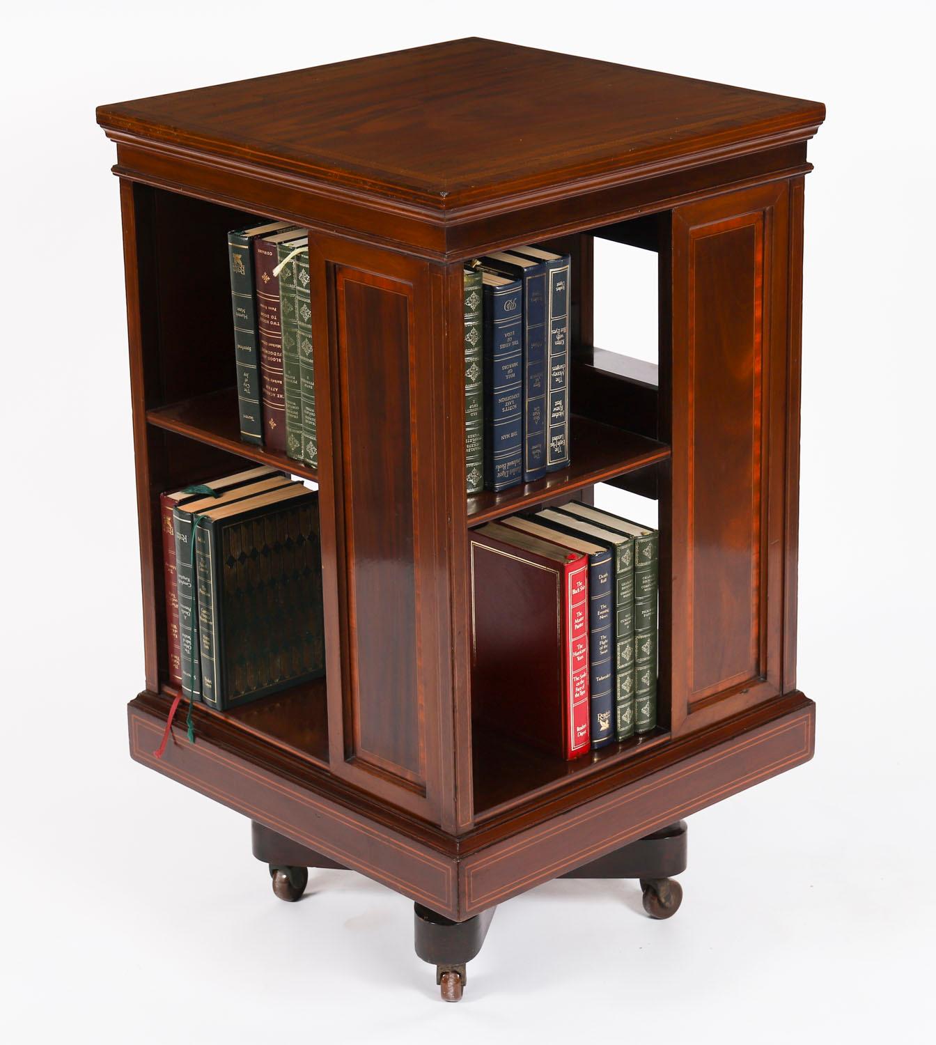 This is an exquisite fine quality antique Edwardian revolving bookcase, circa 1900 in date.

This lovely piece is made of flame mahogany with satin wood crossbanding and line inlaid decoration.

The bookcase revolves on an X cross base with a solid