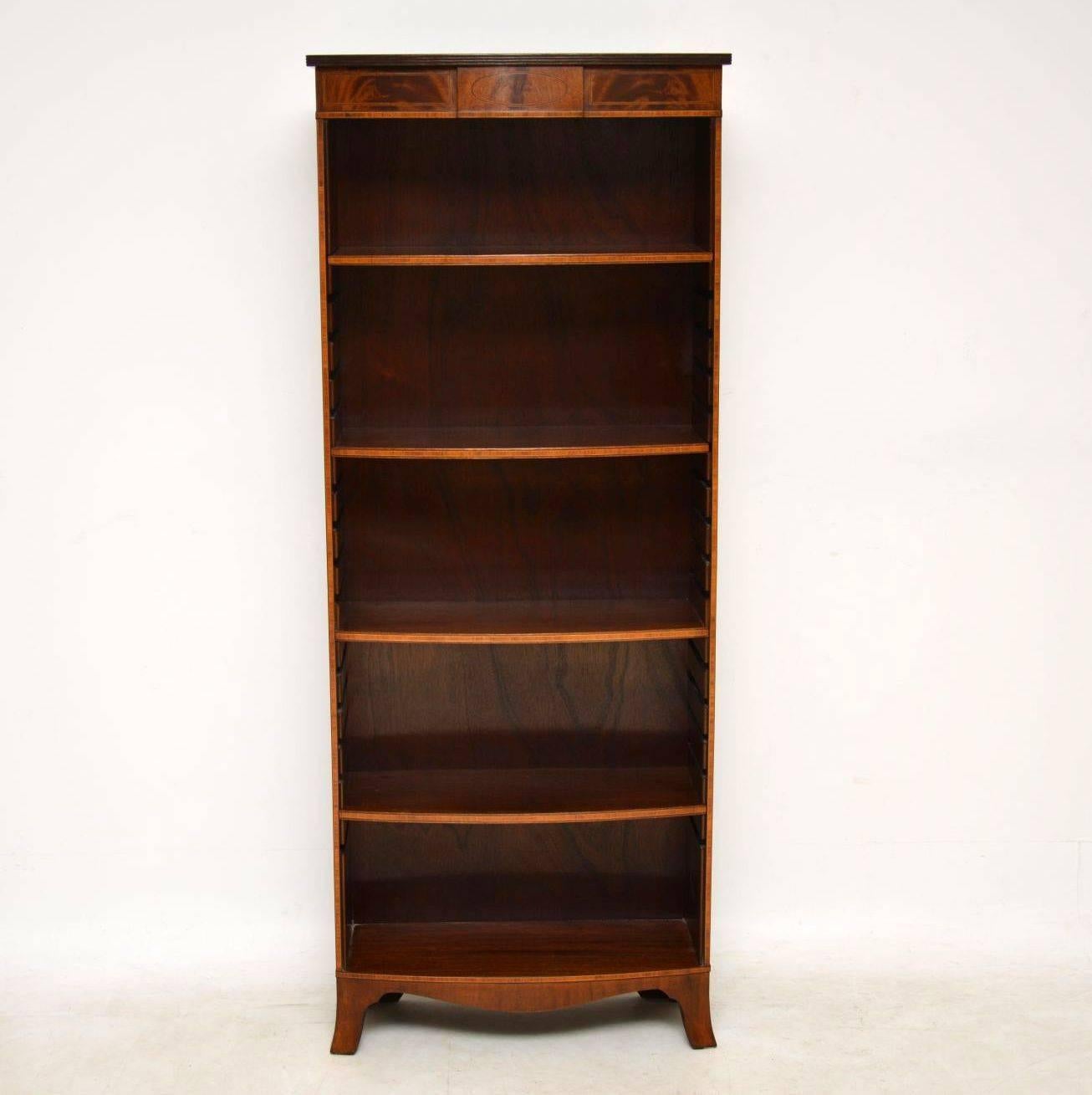 Very smart antique open mahogany bookcase of fine quality, with some lovely features and of small proportions. It’s bow fronted with a reeded top over a flame mahogany panel with various inlays. The mahogany shelves are all adjustable and slot into