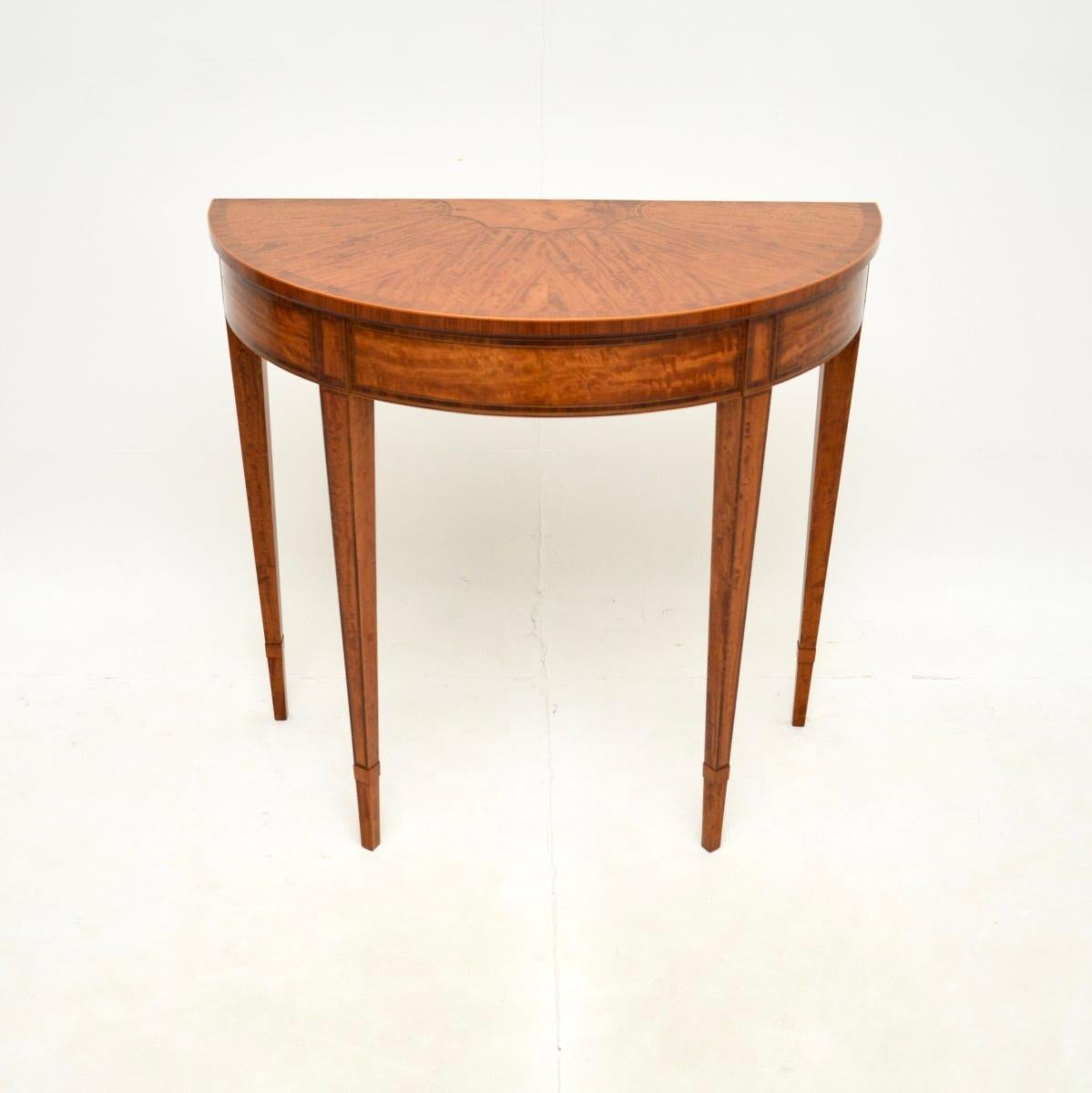 Una consolle antica in legno satinato intarsiato, bellissima ed estremamente ben fatta. Questo modello è stato realizzato in Inghilterra, è in stile Sheraton e si può datare intorno agli anni '20-'30.

È di ottima qualità, con un design elegante e