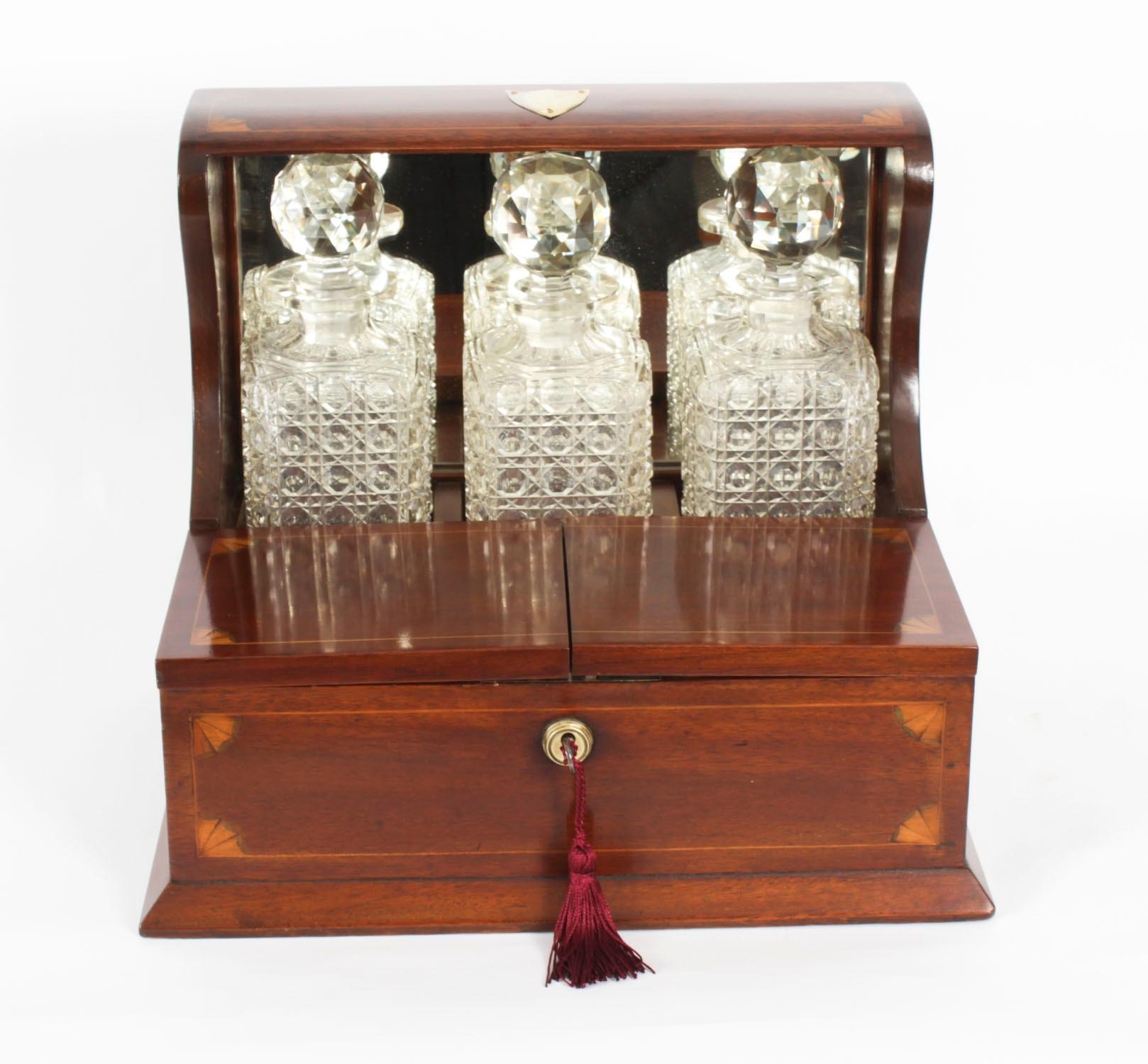 This is a superb antique Victorian walnut cased three decanter tantalus with  fan patterae inlaid decoration, C1890 in date.

It was skillfully crafted with beautiful fan patterae marquetry with line inlaid decoration, stylish brass handles and a