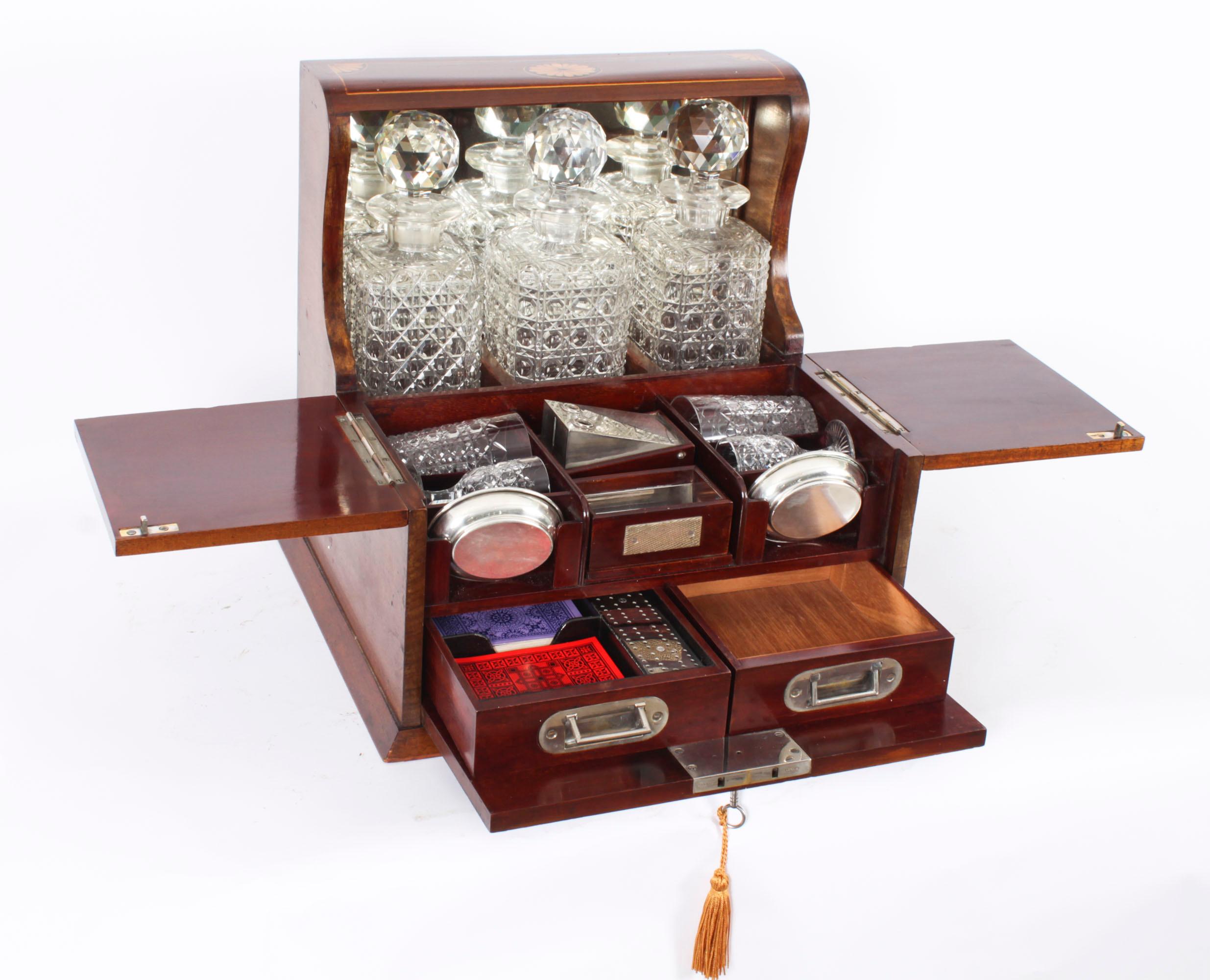 This is a superb antique Victorian walnut cased three decanter tantalus with decorative inlaid decoration and a games drawer, C1890 in date.

It was skillfully crafted with beautiful fan marquetry with line inlaid decoration, stylish brass handles