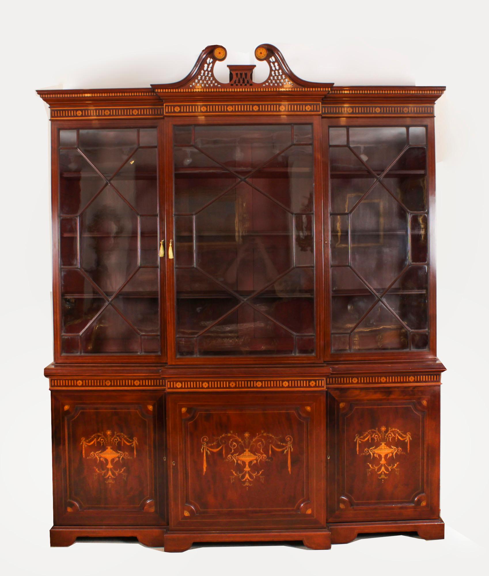This is a beautiful antique late Victorian Sheraton Revival top quality flame mahogany and marquetry inlaid three door breakfront bookcase, masterfully crafted in rich solid mahogany, circa 1890 in date.

It is a truly grand piece decorated with