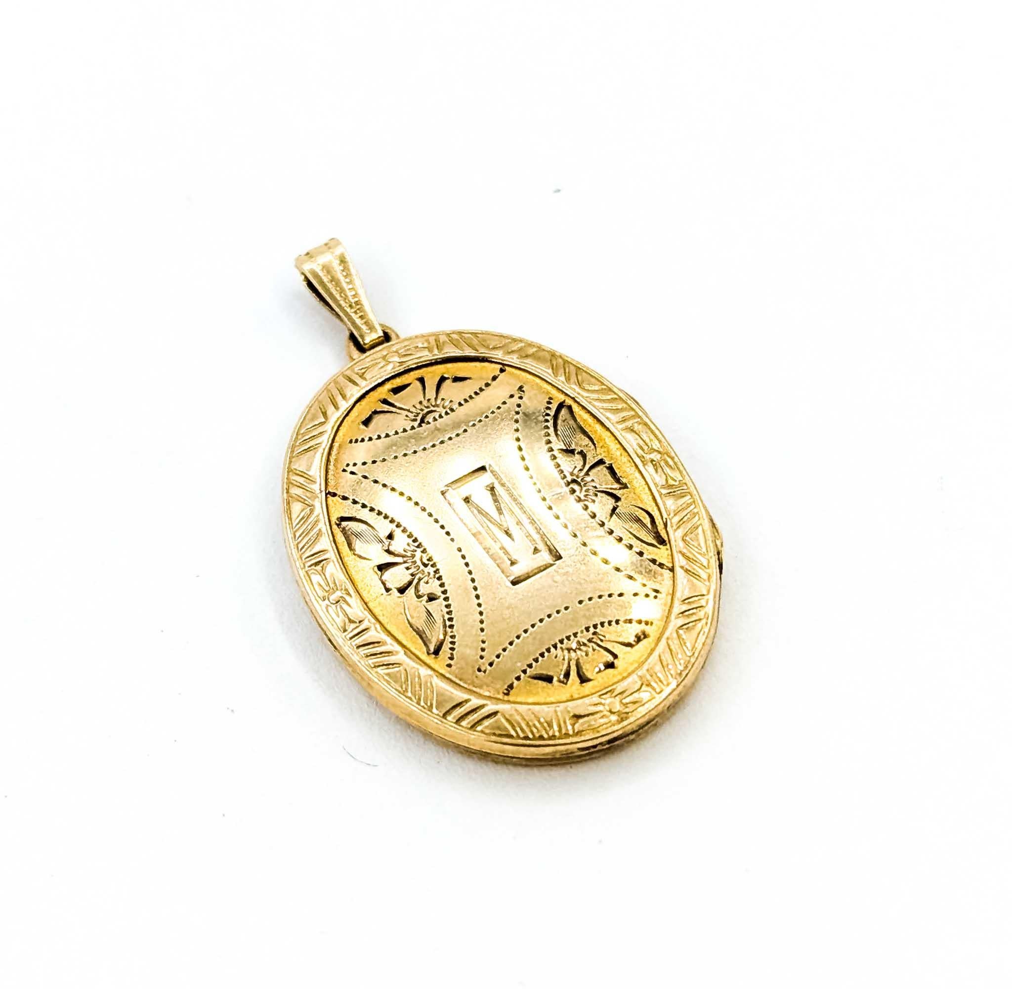 Ce charmant médaillon ovale en or jaune 10 carats est orné d'une bordure délicatement gravée et d'un monogramme 