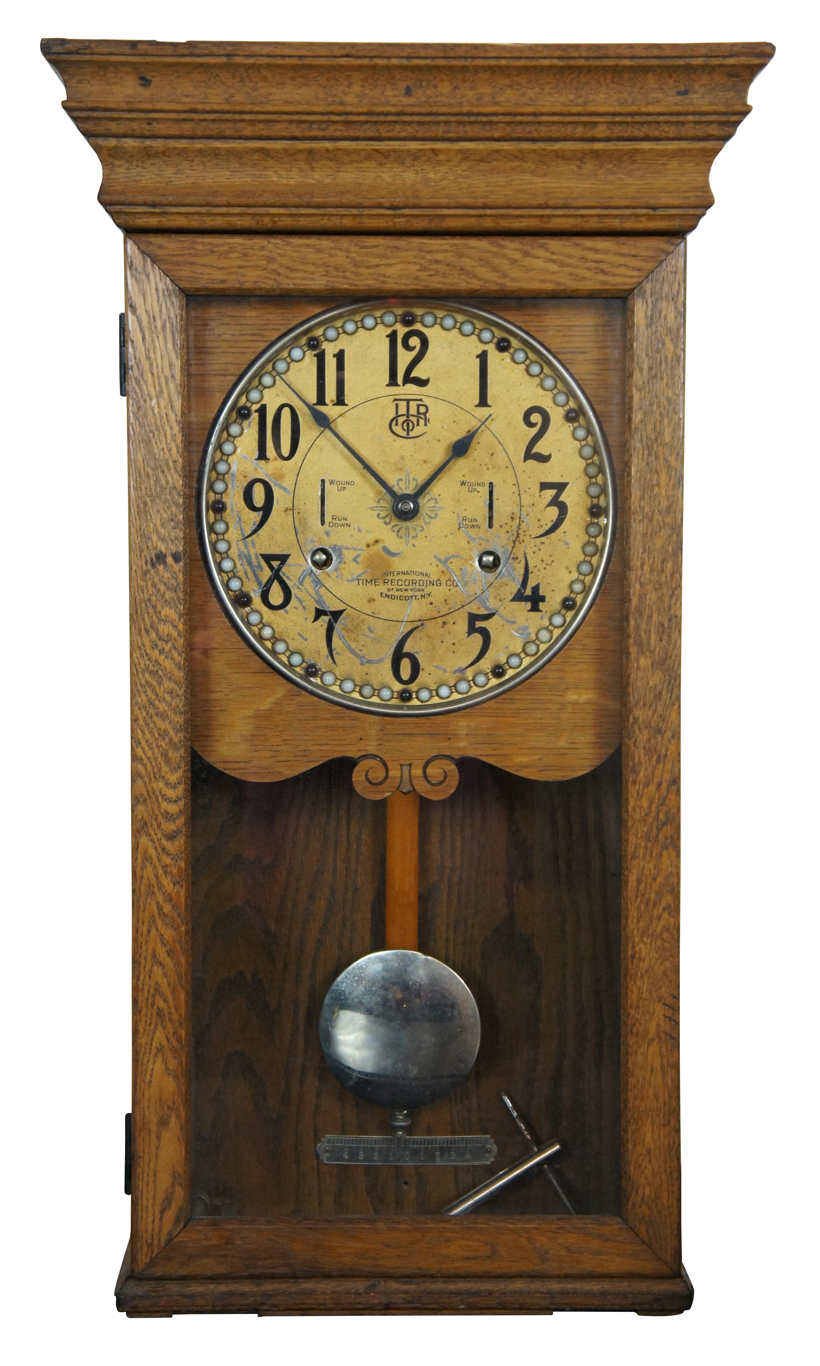 Antique early 20th century oak cased wall hanging clock by the International Time Recording Company of Endicott, New York. Gold painted face is bordered with red and white gemstones. Size: 31