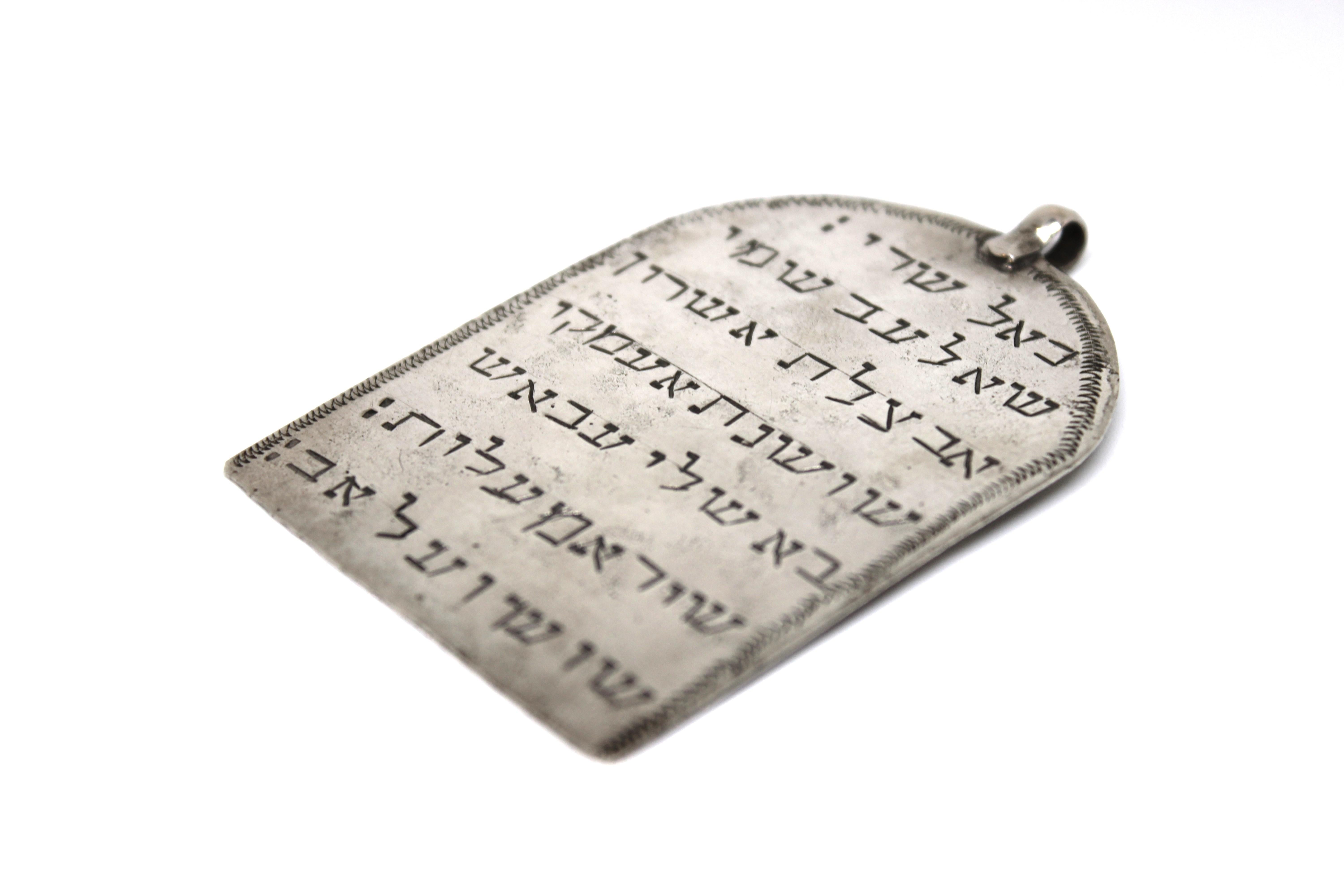 Questo raro amuleto iracheno antico, a forma di tavoletta e realizzato in argento, incarna la profonda eredità spirituale dell'ebraismo mediorientale. La sua forma elegante è incorniciata da un bordo ondulato splendidamente inciso, che aggiunge un