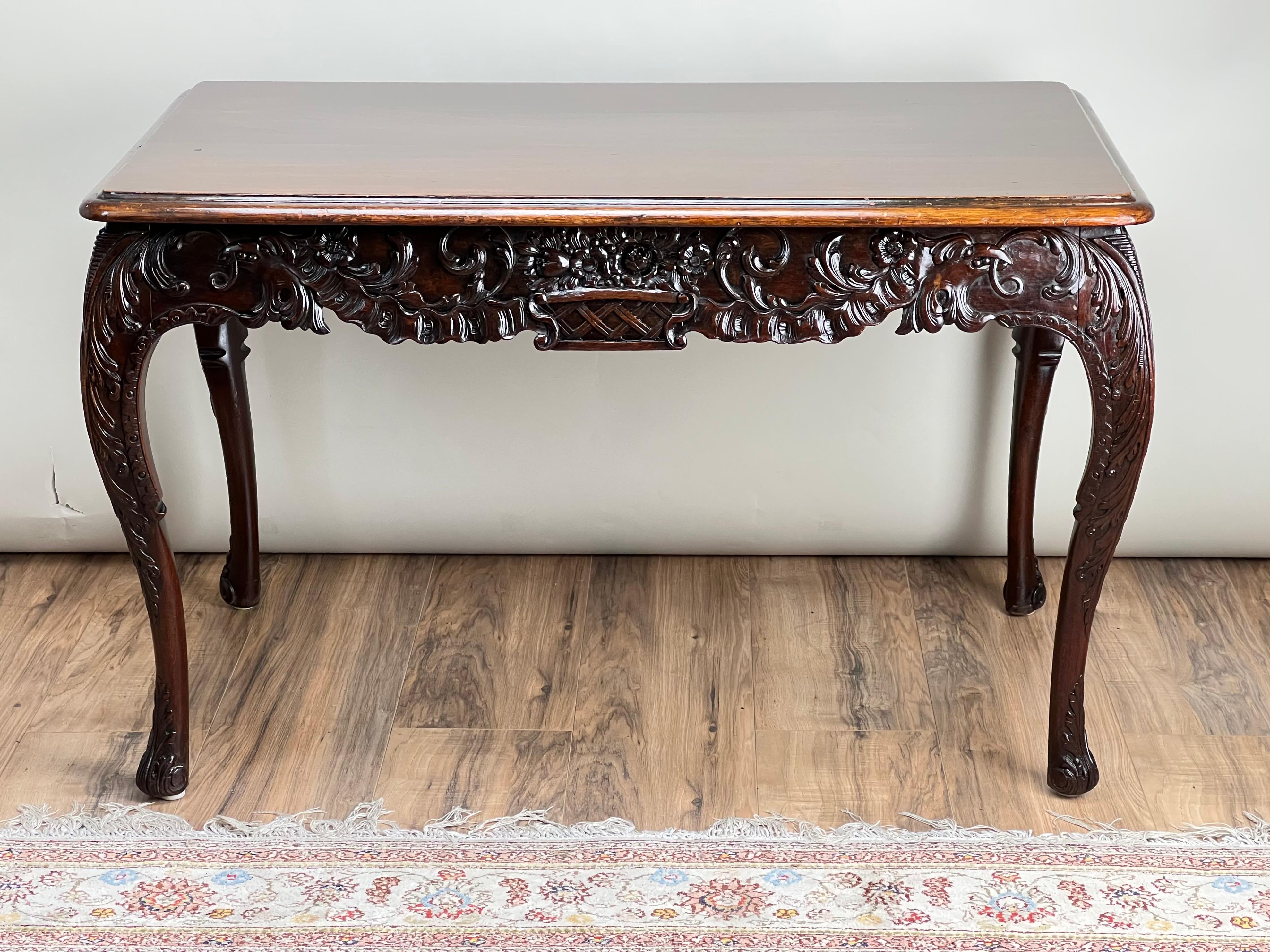 Cette exquise table à thé en acajou irlandais, datant de la fin du XIXe siècle, présente des détails magistralement sculptés à la main qui incarnent l'artisanat irlandais de l'époque. Le plateau rectangulaire, à la patine magnifiquement vieillie,