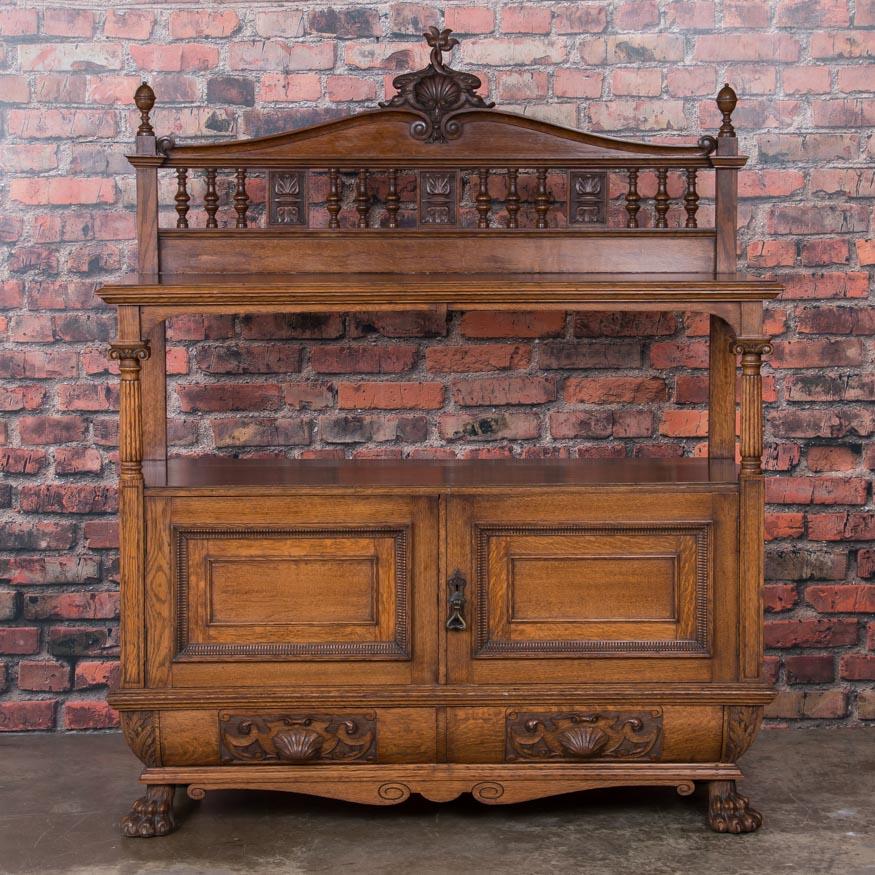 Executed with exceptional detail and craftsmanship, this late 19th century hand carved oak buffet cabinet is from Belfast, Ireland. Of special note are the two carved shell drawer pulls and pawed feet as well as the maker's label inside the cabinet