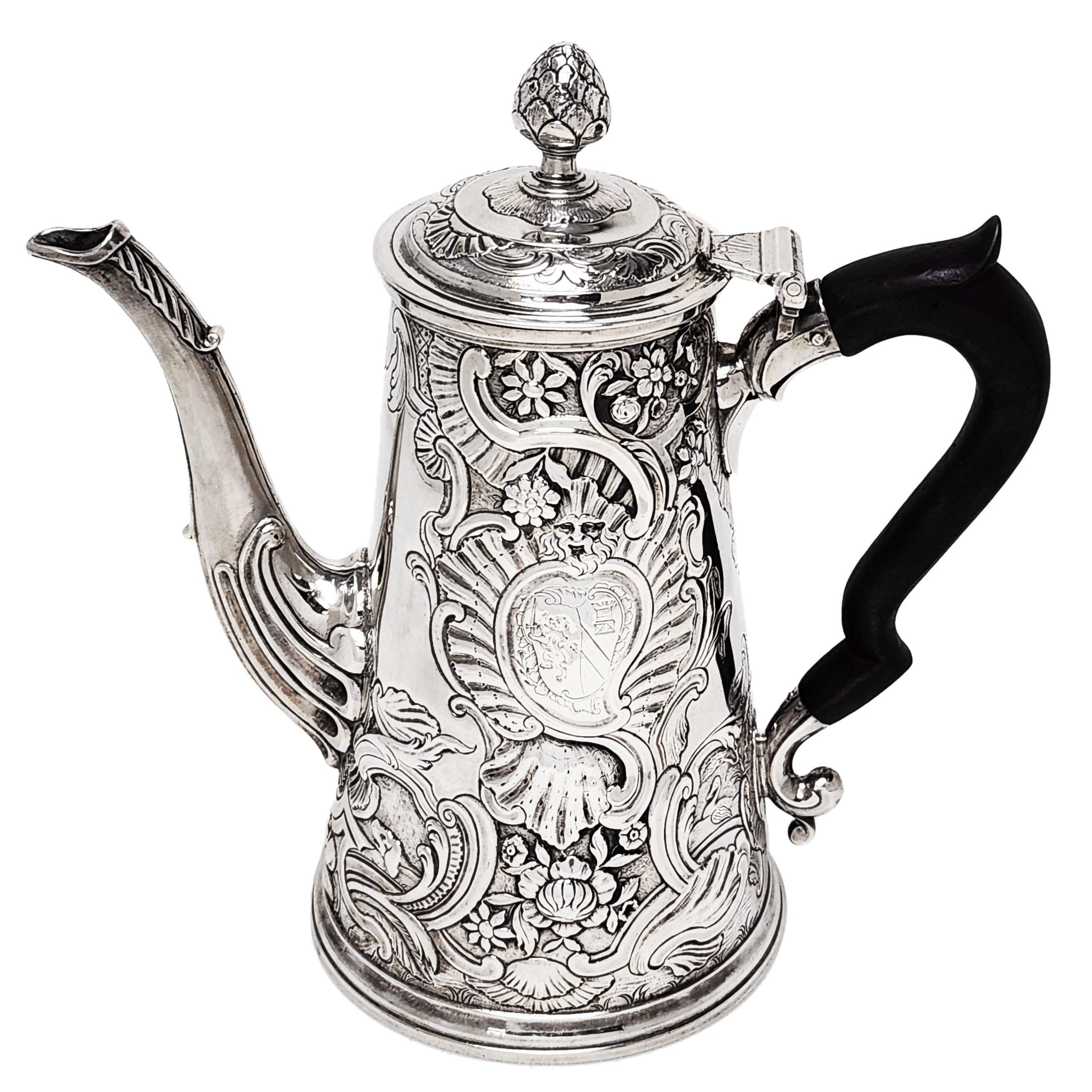 An impressive Antique Irish Rococo Silver Coffee Pot with an ornate chased design embellishing the body, lid and spout of the kettle. Each side of the kettle shows an engraved cartouche, one with an armorial and one with a crest. The chased designs
