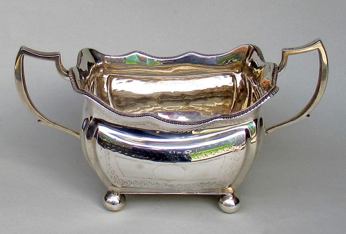 Substantial heavy gauge and in our opinion quite rare Georgian Dublin Irish silver two handle sugar bowl of generous size and of rectangular outline with scrolling angular handles, ogee lobed wavy rim, ending on four ball feet. 

The shaped border