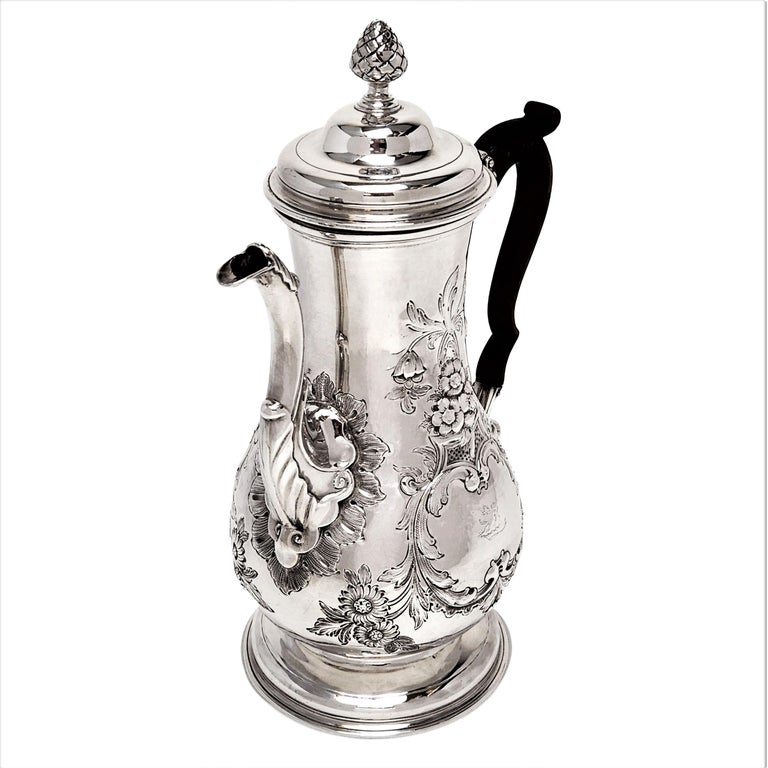 An impressive Antique Irish Provincial Sterling Silver coffee pot with a classic baluster form and decorated with elegant floral chased patterns. The Cork Coffee Pot has a pair of shaped cartouches, one plain and one iwth a small engraved crest