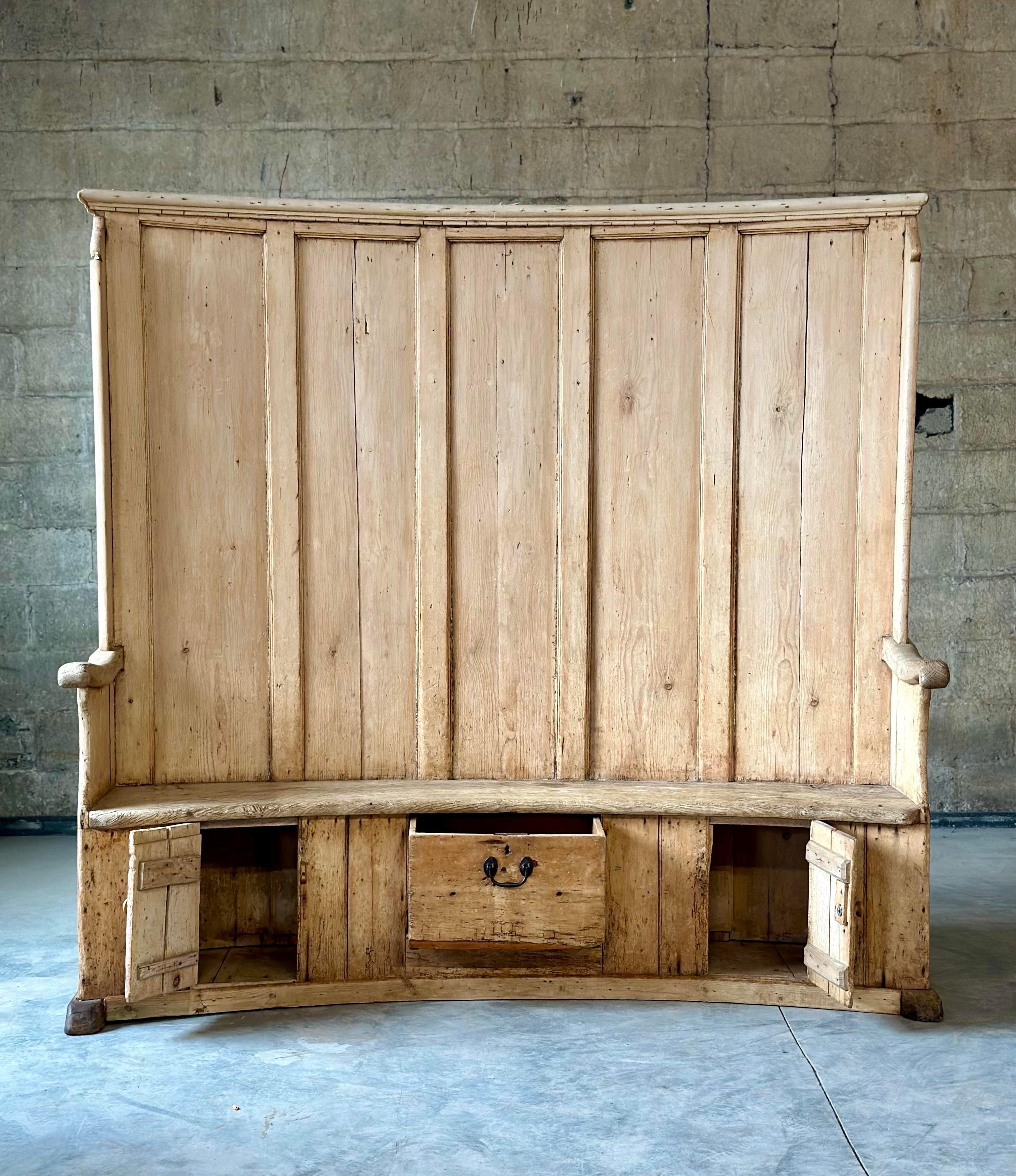 Banc irlandais en pin datant du milieu des années 1800. Un style résolument cool avec des tonnes de rangements - deux grandes armoires à l'arrière et des rangements sous le siège à l'avant. Traditionnellement, un siège était placé près de l'âtre, le