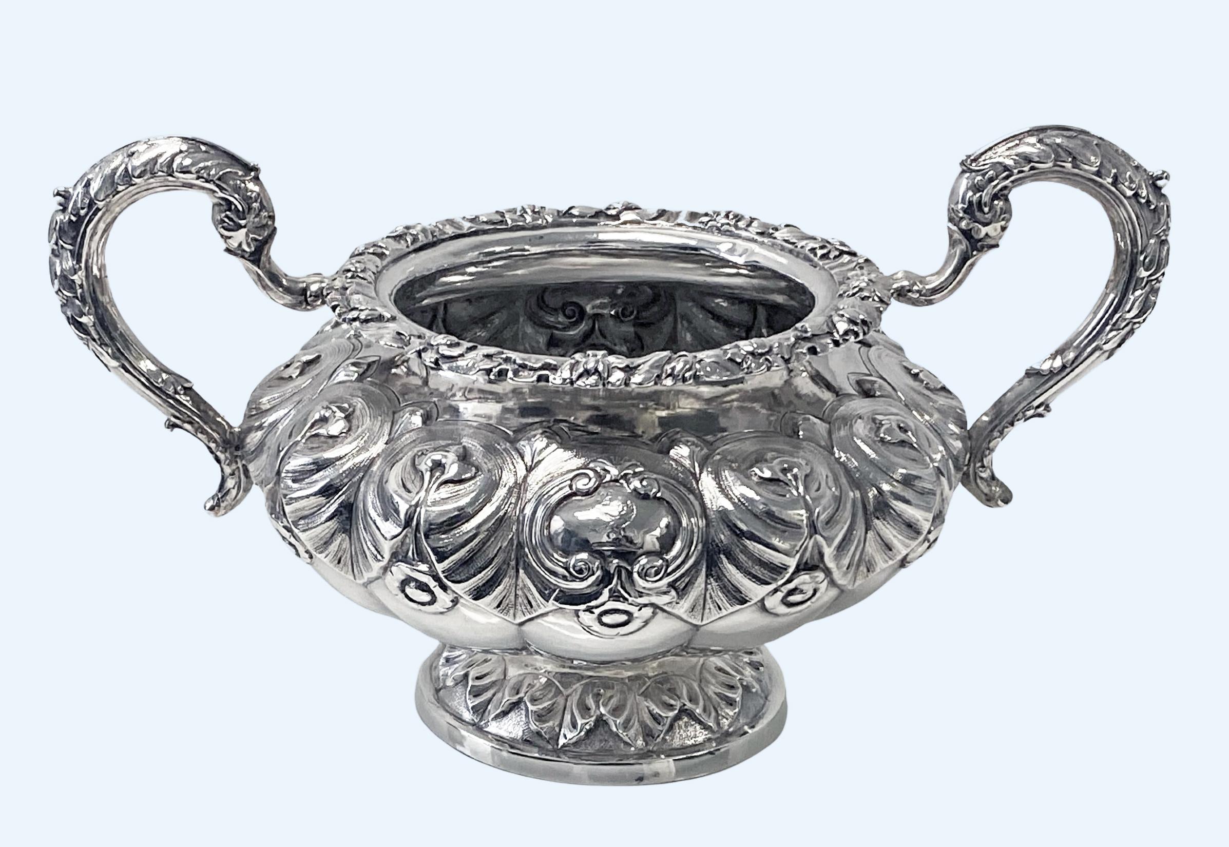 Antique Irish Silver bowl, Dublin 1834 John Moore. Large two handled circular bombe form with repoussé and embossed foliage decoration on partial stippled background, rich foliage leaf capped c scroll handles and foliate rim. Engraved crests of a
