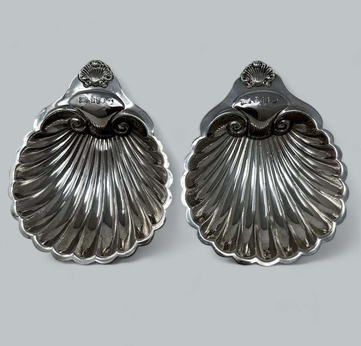 Espléndida pareja eduardiana de fuentes para mantequilla o bon bon de plata irlandesa, con forma de concha de almeja, elevadas sobre tres soportes de bola. 

Marca de W E para platero de Cork William Egan & Sons 
Calle Patrick 32, Cork.
Sello de