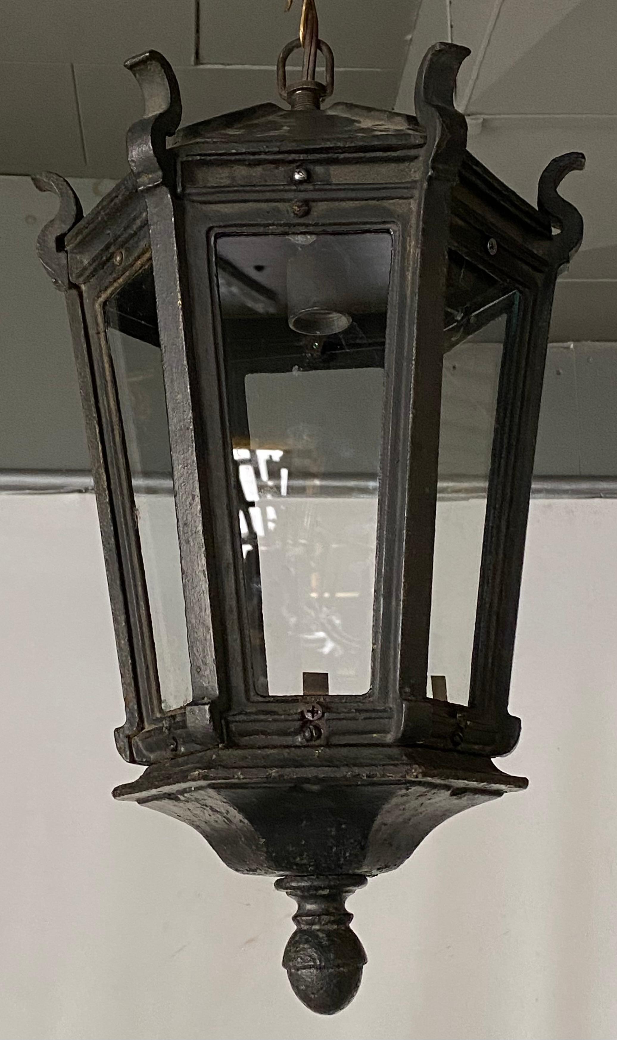Handsome and impressive iron ceiling hanging lantern with great aged patina for either interior or exterior lighting. The shaped crown top leads down to a hexagonal body with glass panels.
Chandelier, pendant light, hanging lantern.