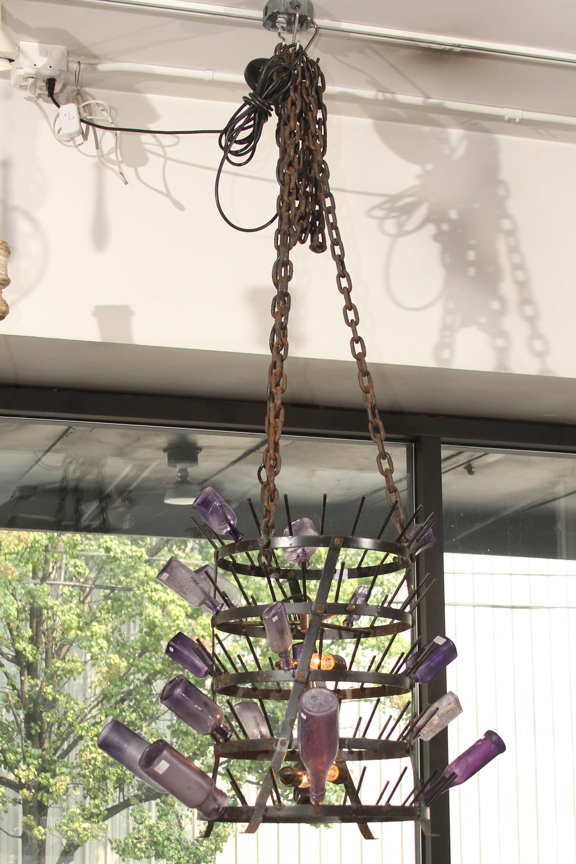 Great looking antique iron bottle rack as chandelier. Four lights, very long chain, so it can fill a tall staircase or be shortened for an 8ft ceiling. (Bottles are not included, but are available for purchase-ask dealer) great for a wine cellar or