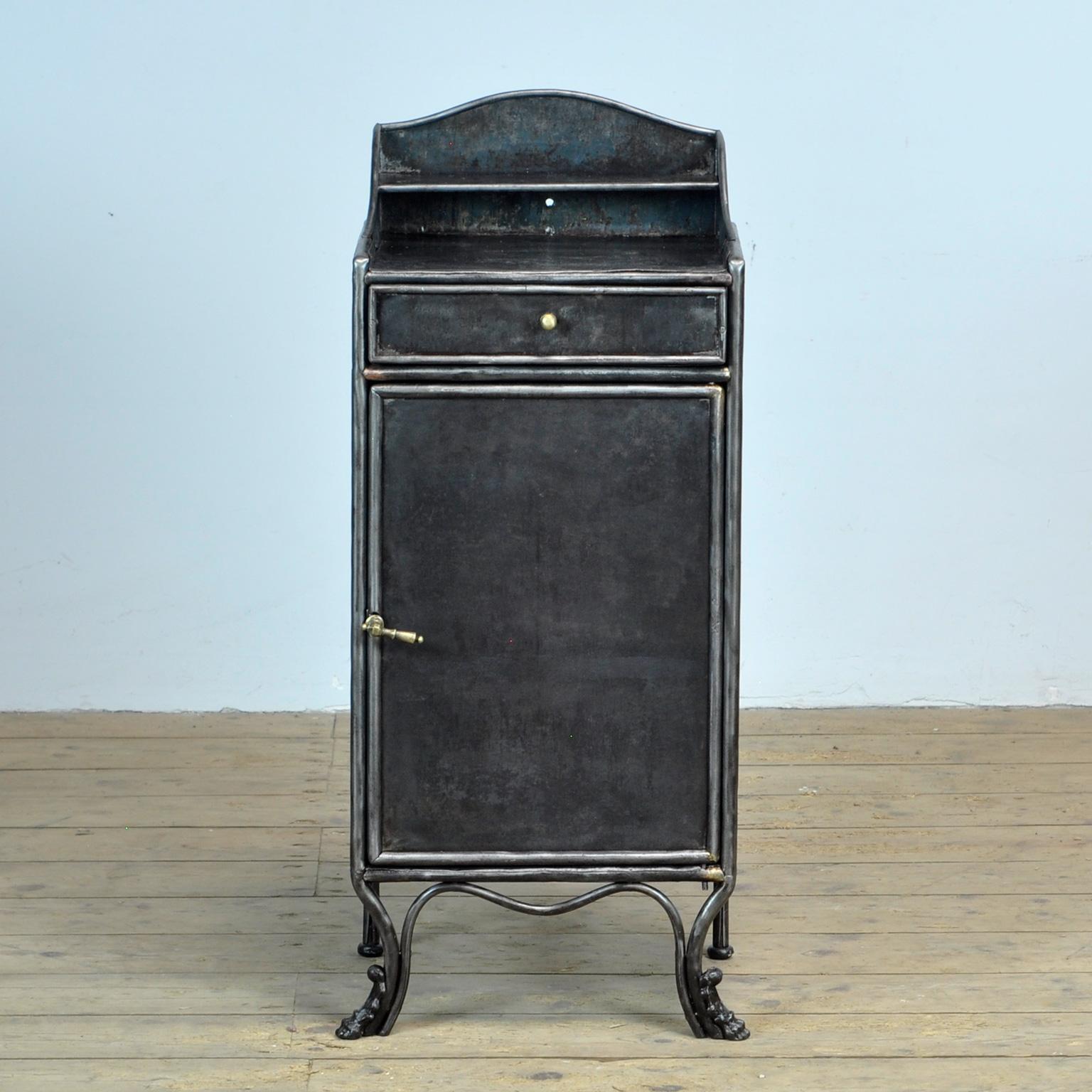 Bedside table made of iron with a bronze handle/knob and a beautiful cast iron detail on the front legs. The cabinet is stripped of the paint and polished. Treated against rust. Circa 1920. 