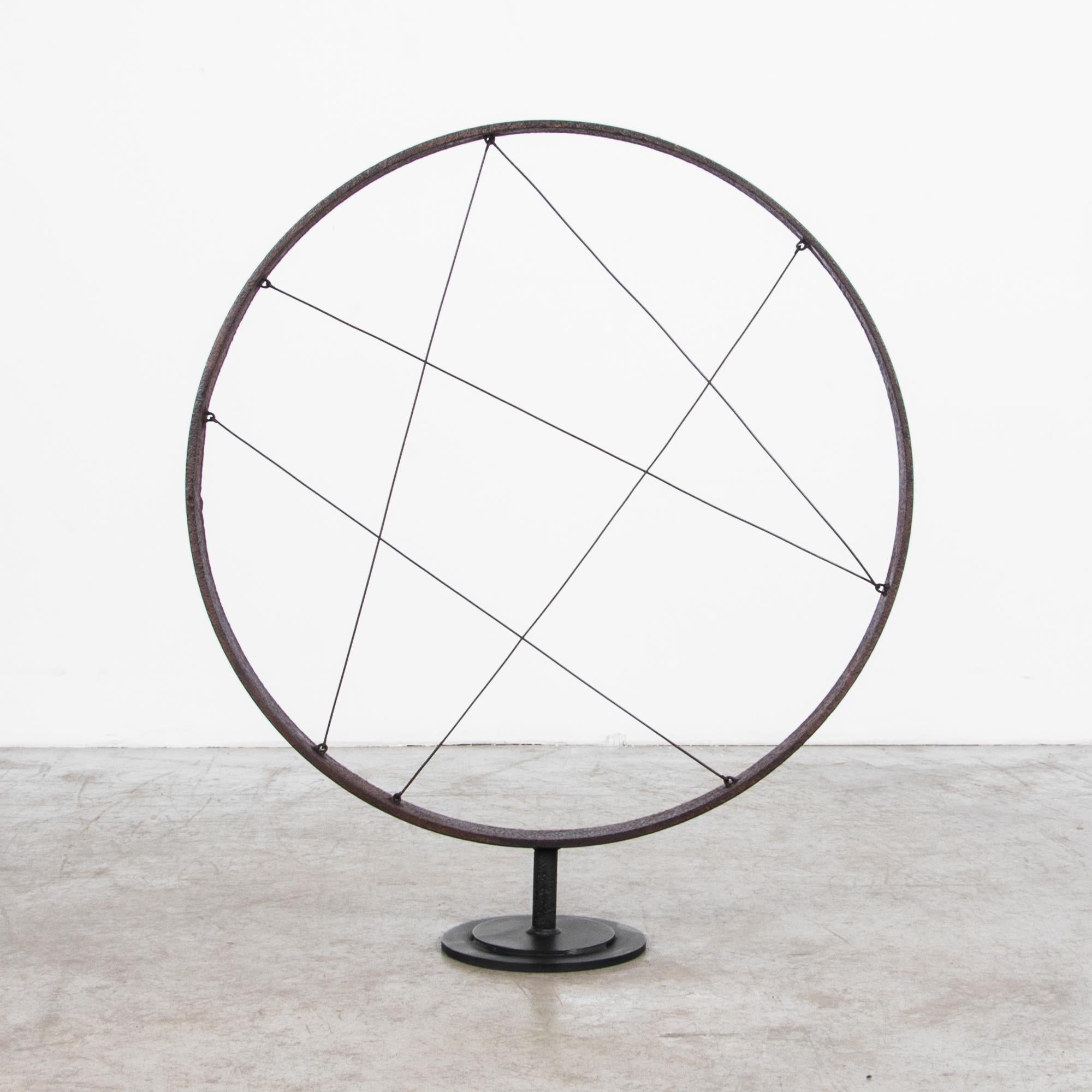 This iron sculpture was made in Central Europe, circa 1900. A circular iron band is crisscrossed by slender iron cables in an abstract, geometric design. The weight and texture of the dark metal contrast effectively with the minimal design. This