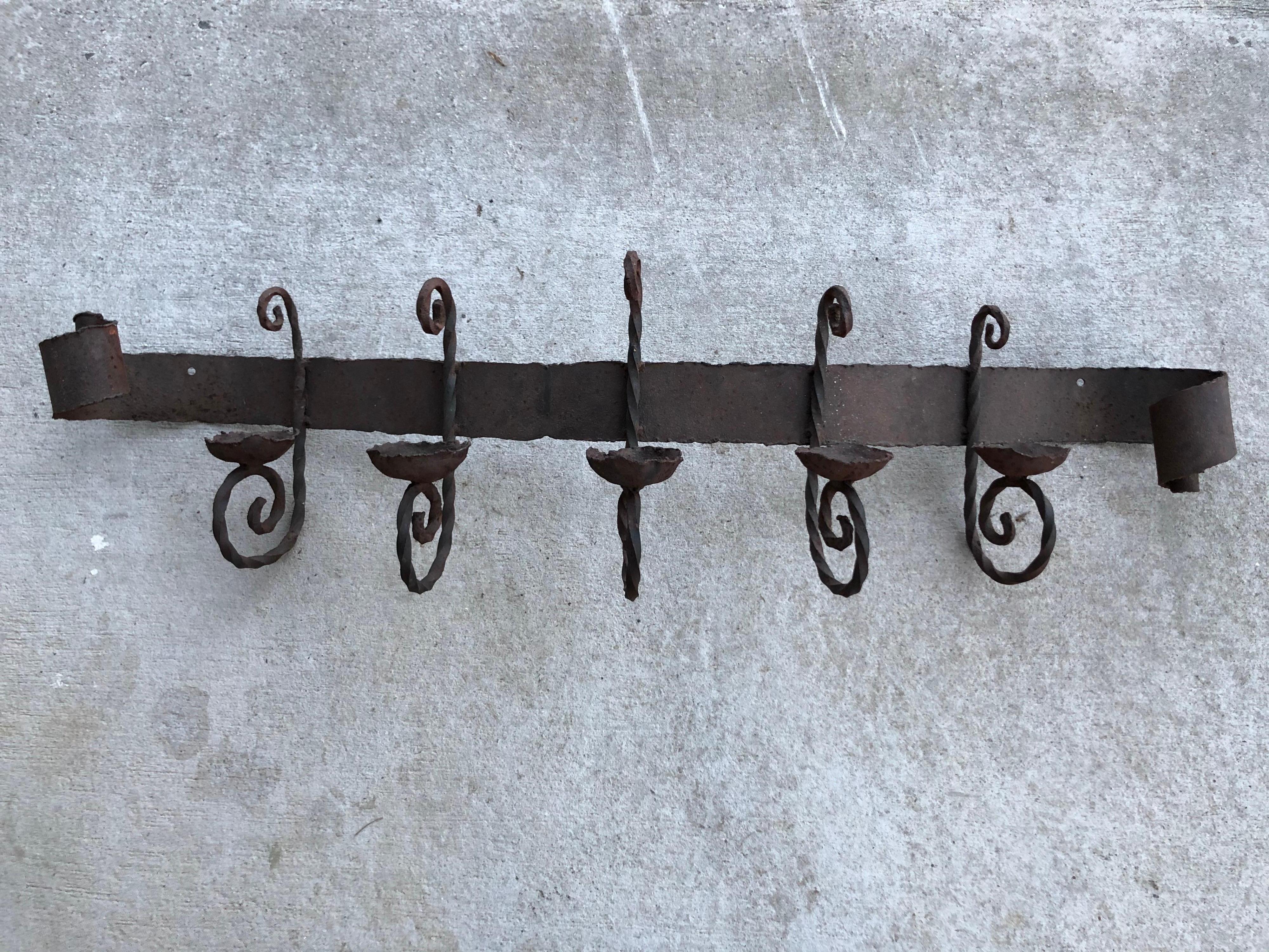 Antique iron wall sconce. Perfect for above a mantel or bed / headboard. Holds 5 candles. All handwrought with rolled scroll like ends and twisted candle holders. Rustic style perfect for that stucco style hacienda. Arched back. Attaches to wall on