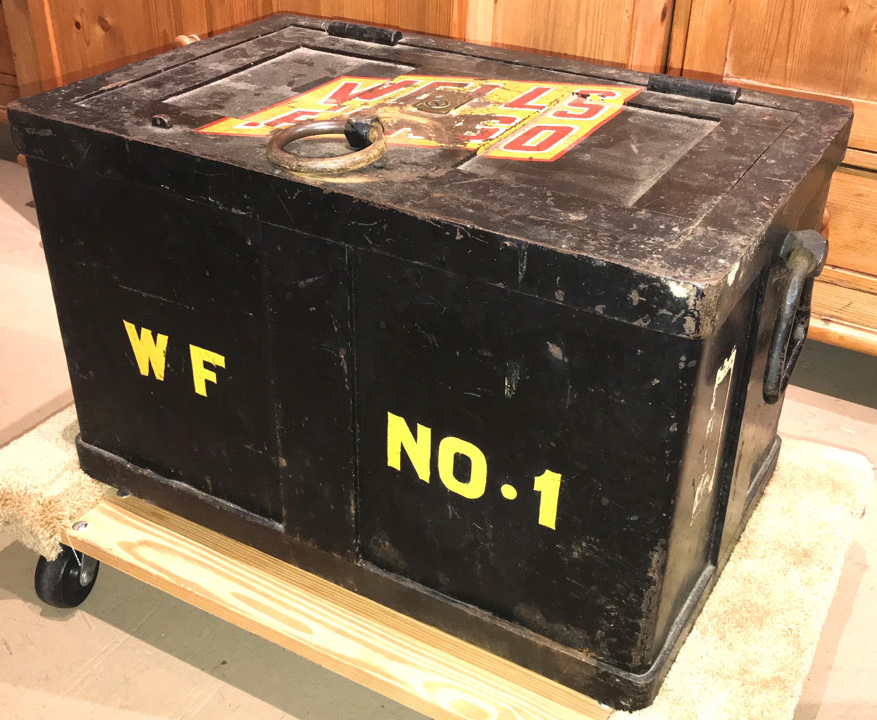 A solid iron railroad strong box,  with top door and side handles intact, repainted at some point in time with black surface, including paint decoration for Wells Fargo in a yellow and red logo on its top, as well as WF No.1 in yellow on the front