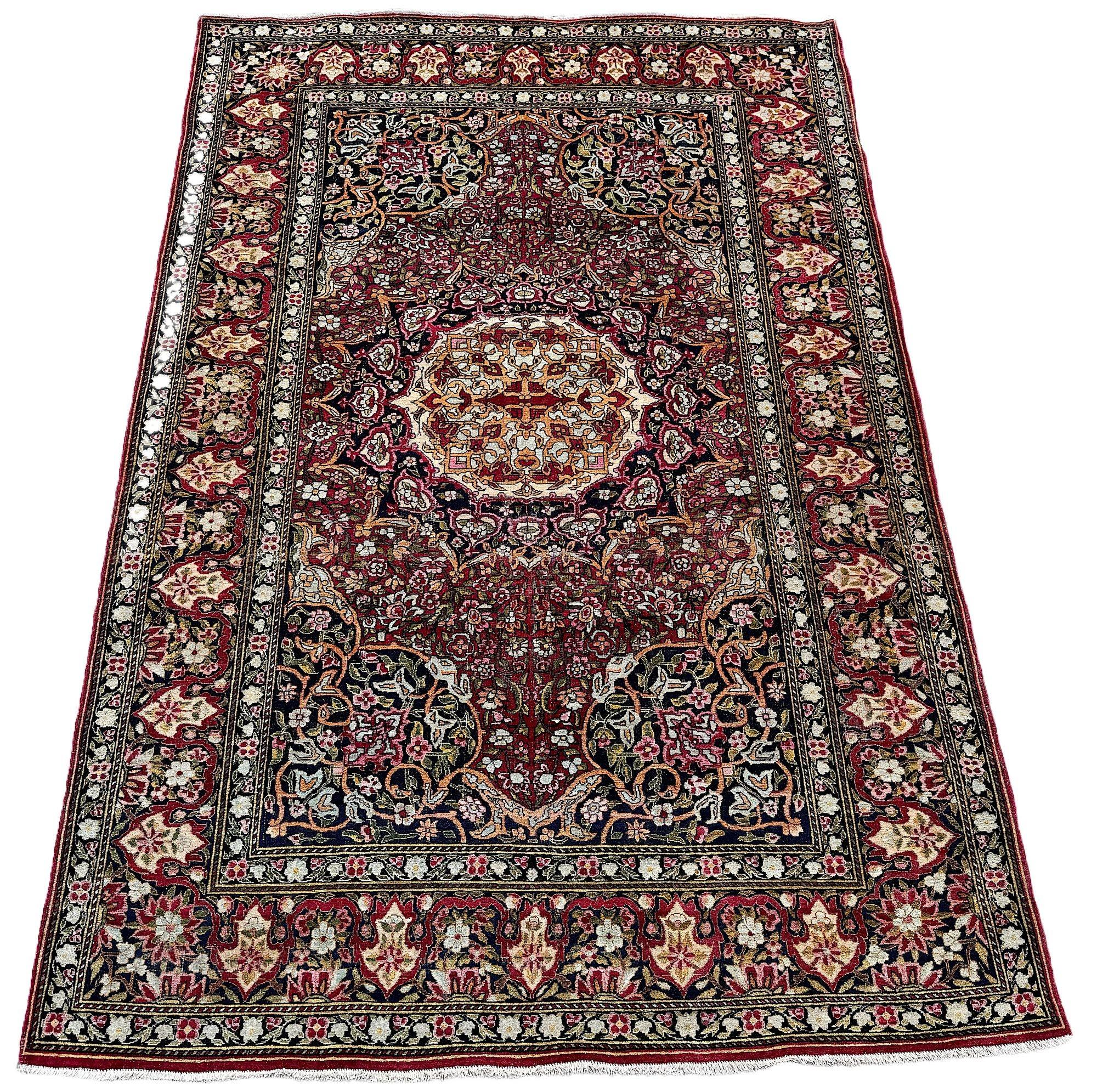 Ein fabelhafter antiker Isfahan-Teppich, gewebt um 1900. Das Design zeigt ein großes rundes Medaillon auf einem sattroten Feld aus Blumen und Ranken, das von einer eleganten roten Bordüre umgeben ist. Fein gewebt mit wunderbaren Sekundärfarben in