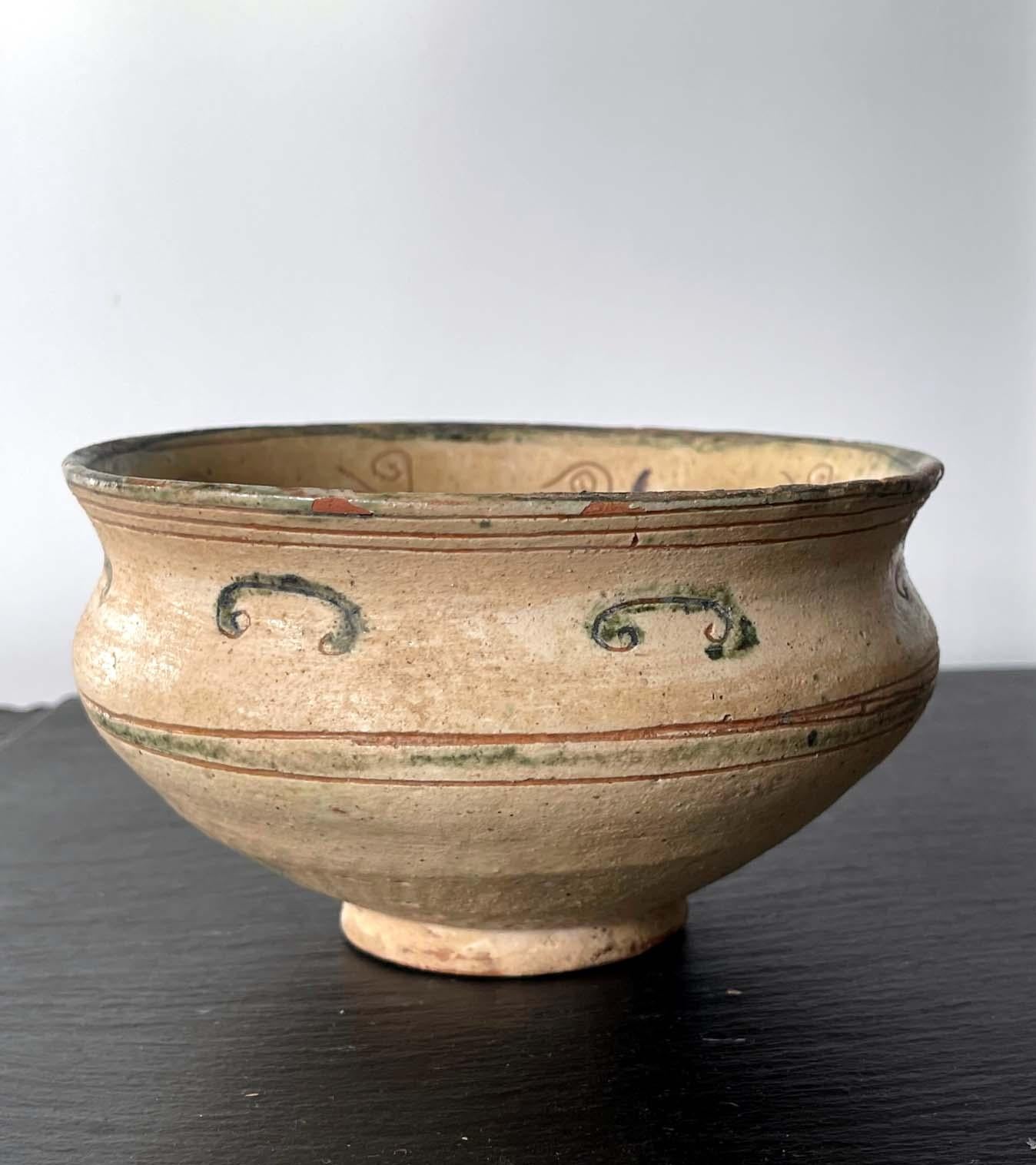 A small Islamic ceramic bowl circa 11-12th century, possibly from Nishapur or Aghkand area of Persia. The elegantly shaped bowl with a slightly flared opening is supported on a small foot rim. The earth ware body of the bowl was made of a red clay,