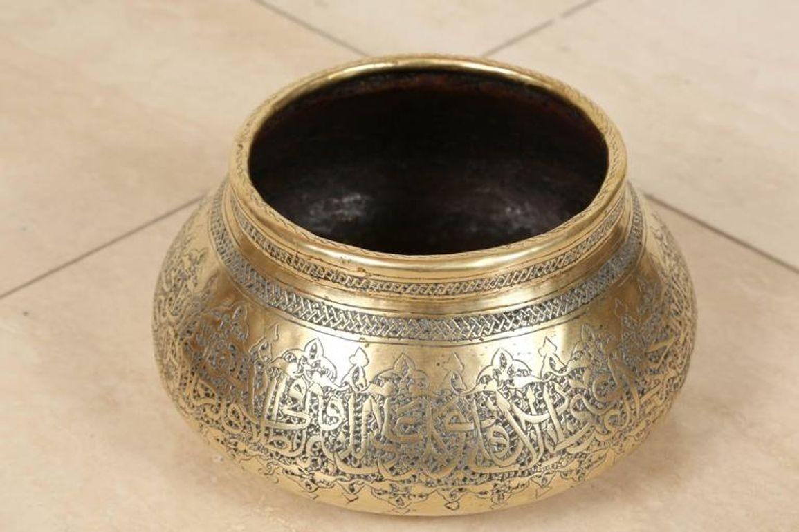 Antique bol en laiton mauresque du Moyen-Orient gravé avec la calligraphie arabe Thuluth.Le bol en laiton poli est abondamment ciselé avec des vignes et des motifs végétaux et inscrit avec des versets islamiques du Saint Coran.Ce bol a été