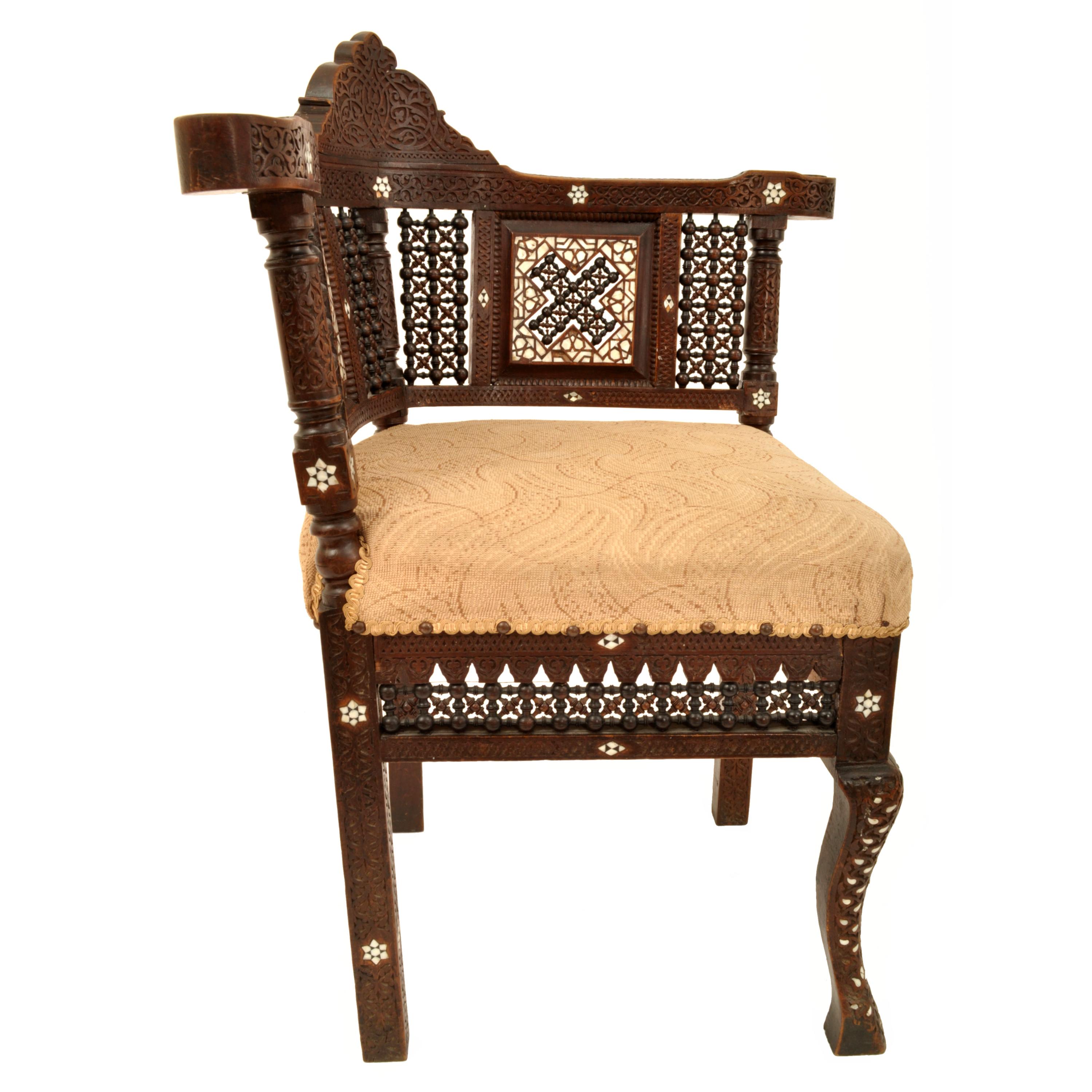 A fine antique 19th century Islamic Moorish style inlaid corner chair, Damascus work from Syria, circa 1880.
The corner chair is made from hardwood and has a crest to the back with Arabesque carving, the continuous armrest with corresponding carving