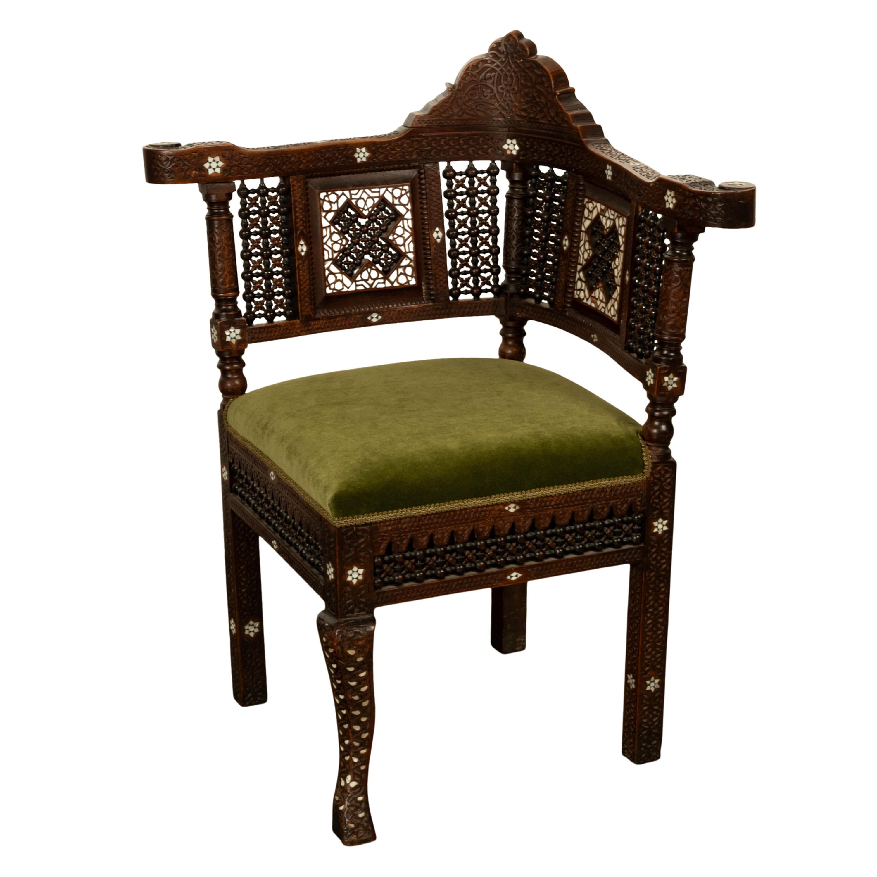 A fine antique 19th century Islamic Moorish style inlaid corner chair, Damascus work from Syria, circa 1880.
The corner chair is made from hardwood and has a crest to the back with Arabesque carving, the continuous armrest with corresponding carving