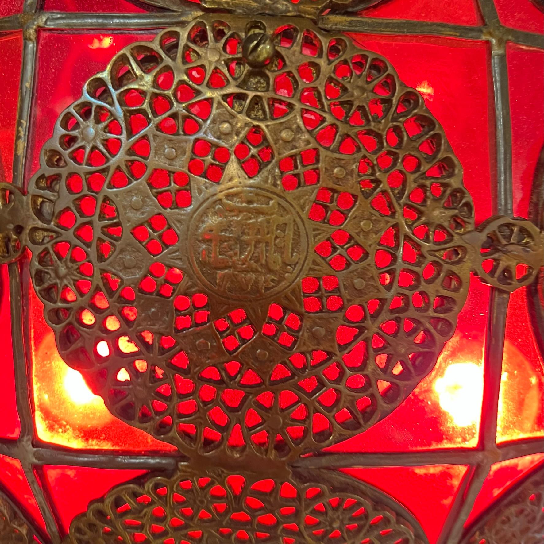 Hanging leaded glass lamp in spherical shape and bronze stem with Islamic poetry in cartouches over red glass.  With two standard sockets each with brass on/off pulls.  In very good condition, with repaired crack and small chip losses to one small